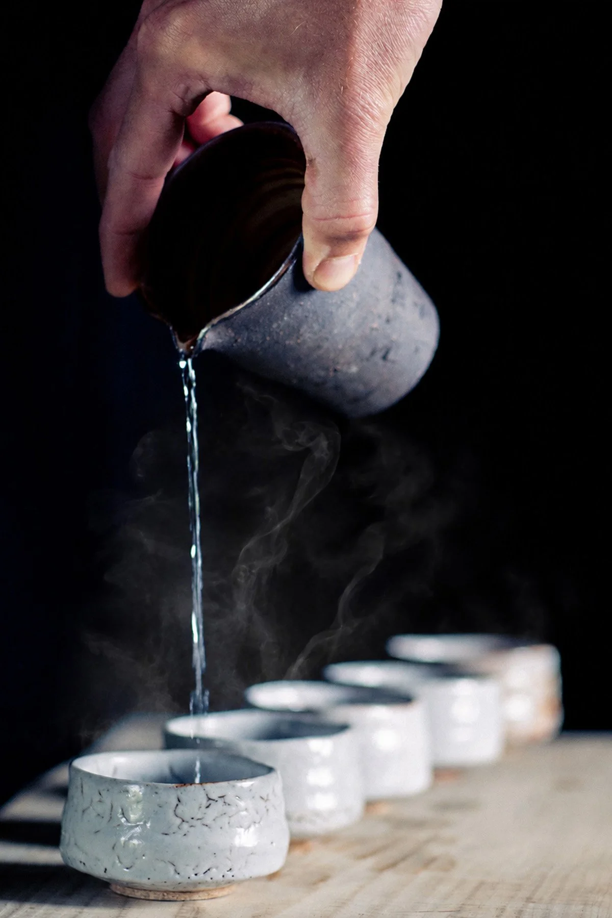 Pouring tea from a Chahai into handmade ceramic cups during a quiet daily tea ritual.