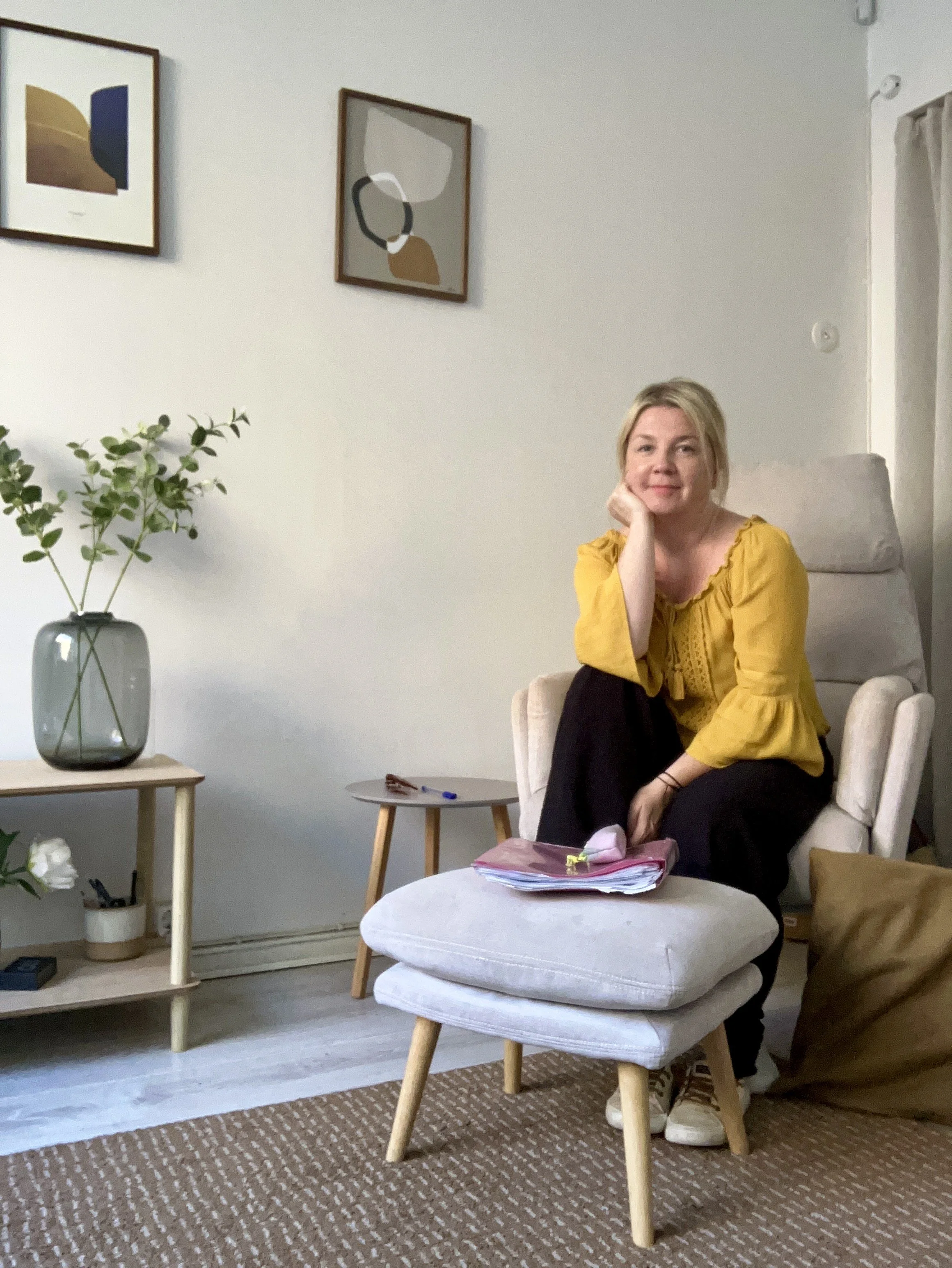 Lyhytterapeutti Kati Eskelinen hymyilee kameralle Terapiahuoneella.