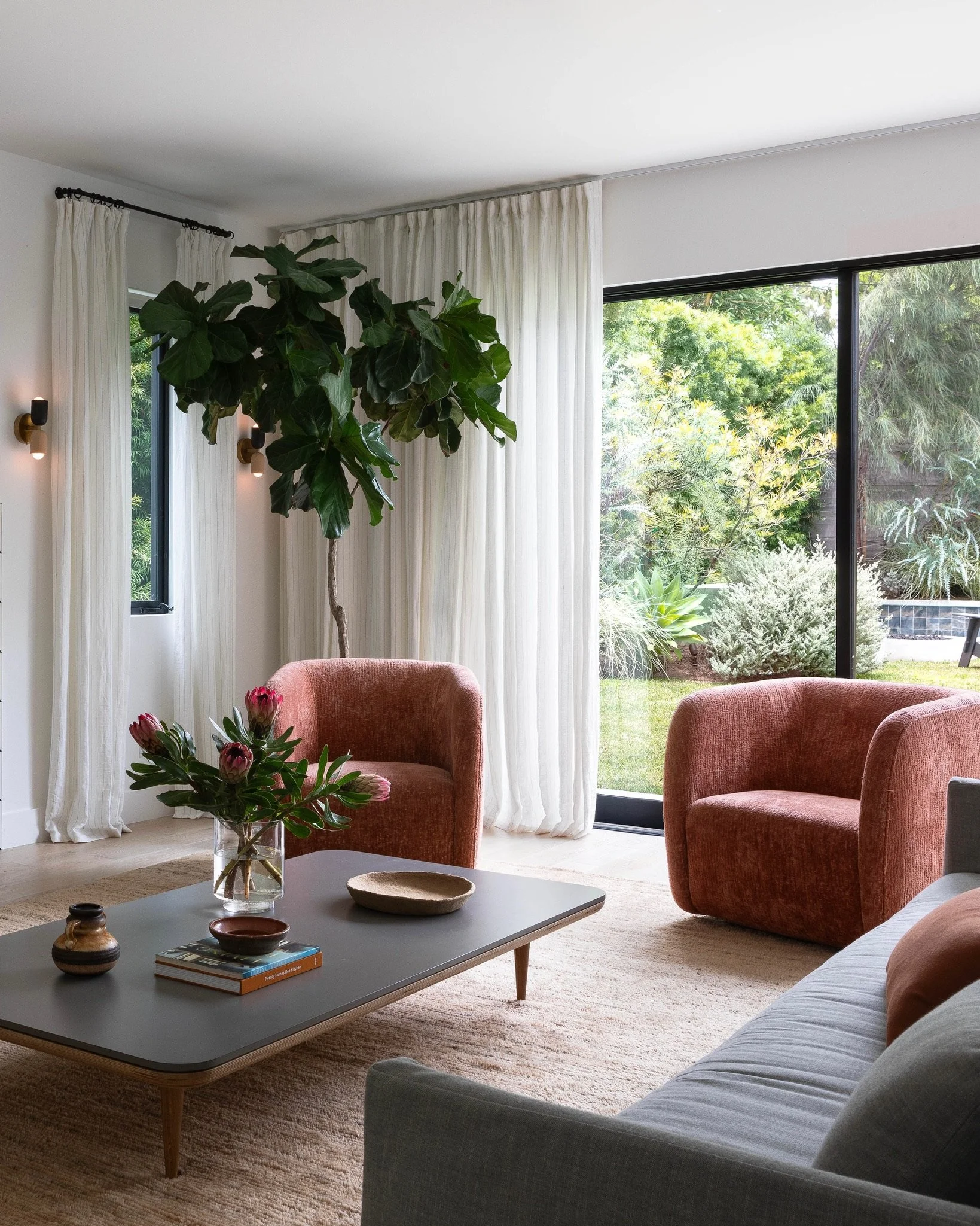 Los Angeles living room with sculptural lounge chairs, custom drapery, layered natural textures and seamless indoor-outdoor living.