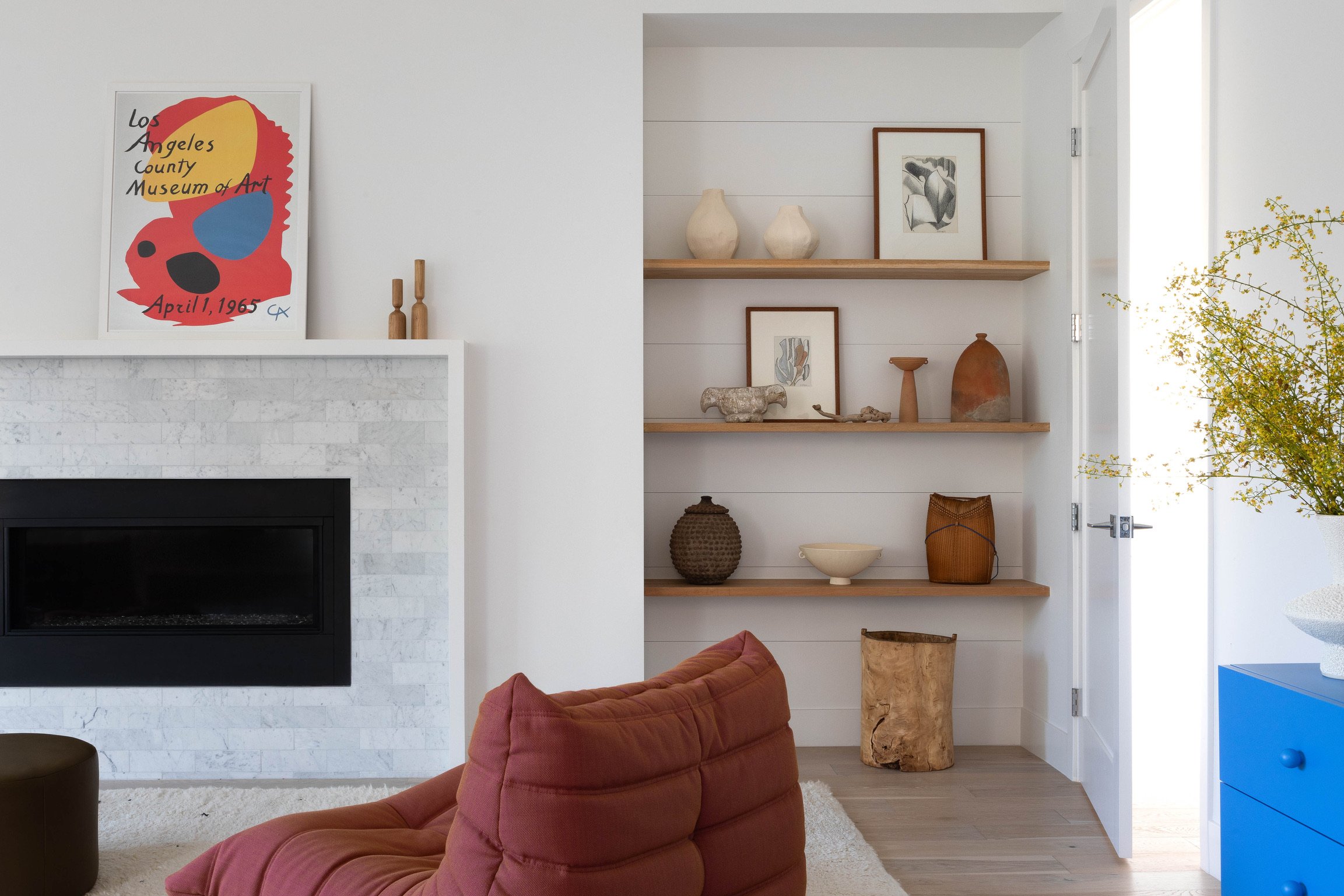 Los Angeles living room with modern fireplace, custom built-in shelving, sculptural furniture and curated art.