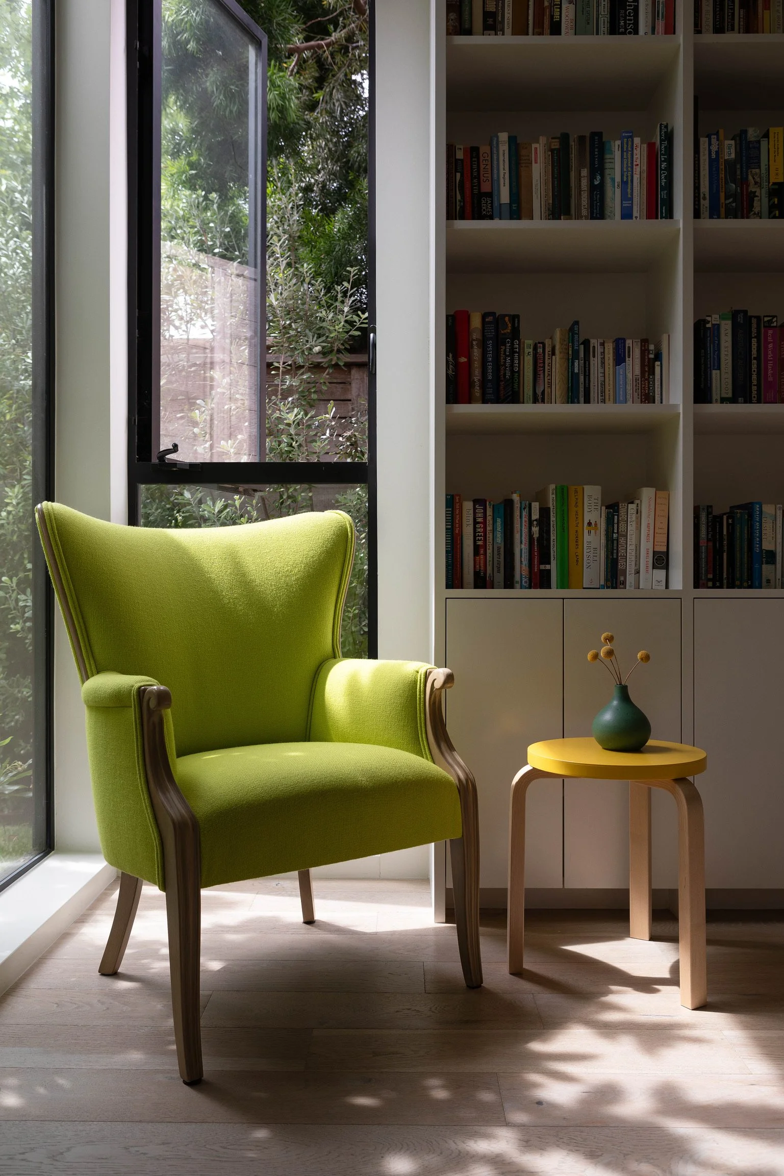 Los Angeles reading nook with vintage green armchair, custom built-in bookshelves and floor-to-ceiling windows.