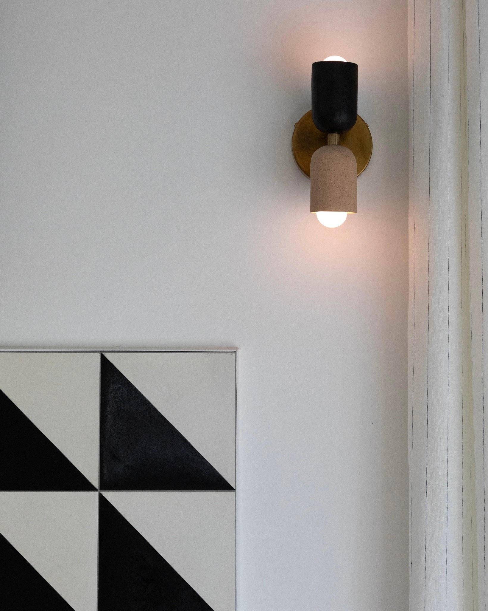 Los Angeles modern interior with geometric black-and-white tile, sculptural wall sconce and custom drapery.