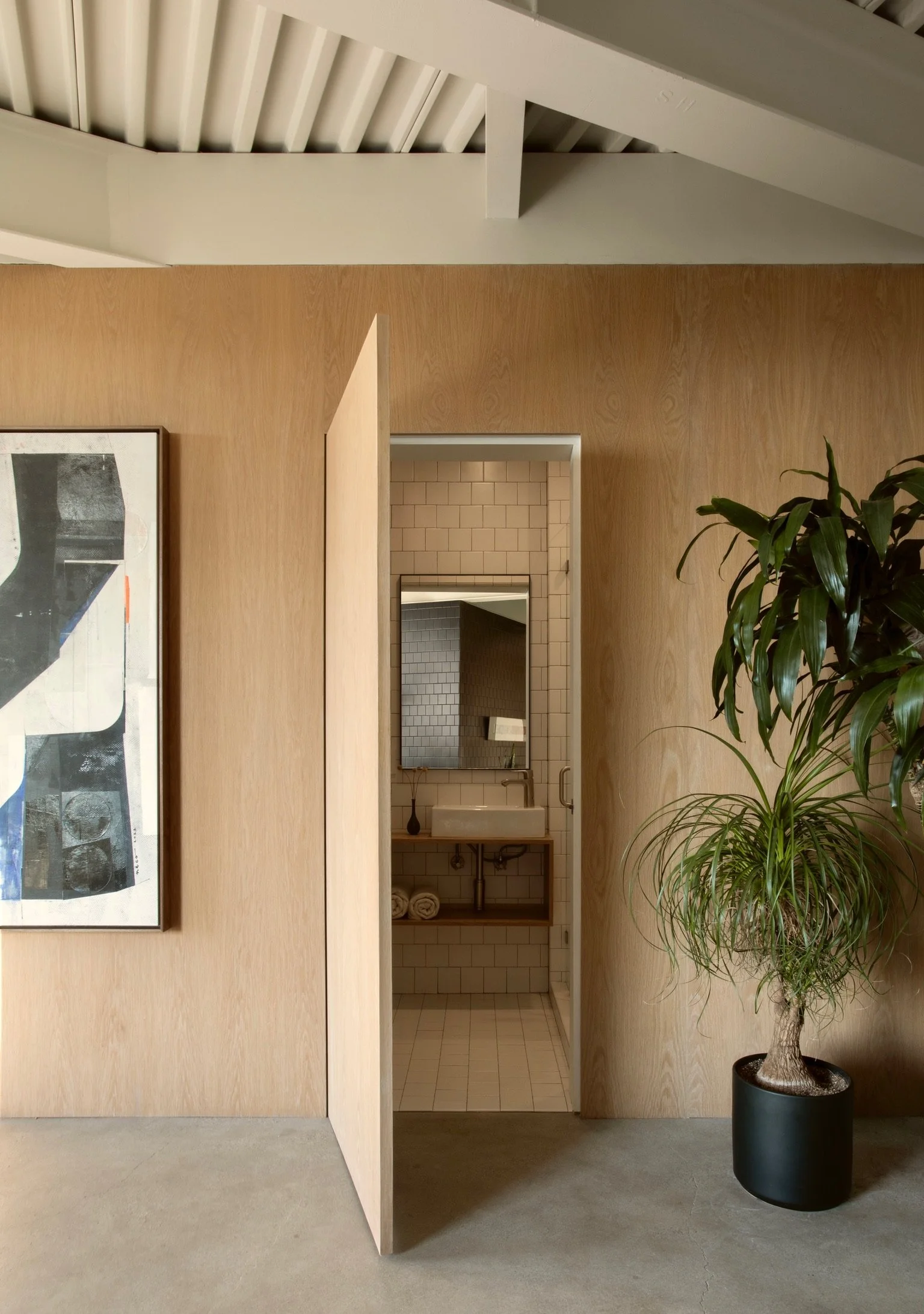 Los Angeles midcentury modern interior with open powder room, curated artwork and indoor greenery.