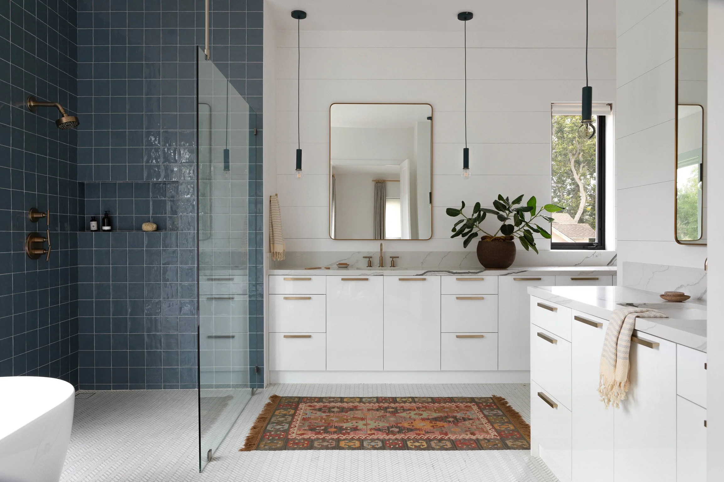Los Angeles primary bathroom with blue tile shower, custom white vanity, marble countertops and brass fixtures.