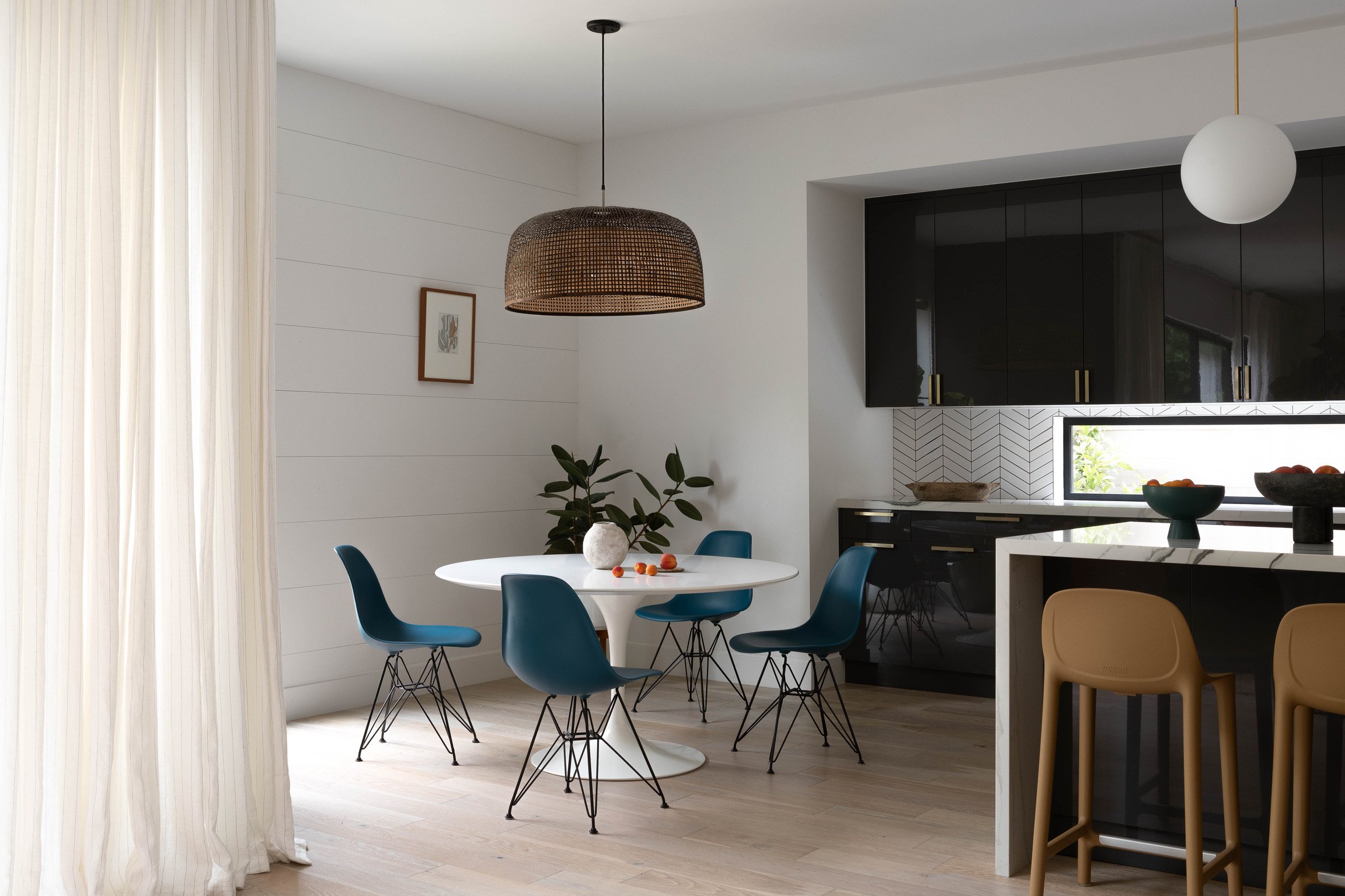 Los Angeles breakfast nook with modern dining chairs, woven pendant lighting, custom drapery and an open-concept kitchen.