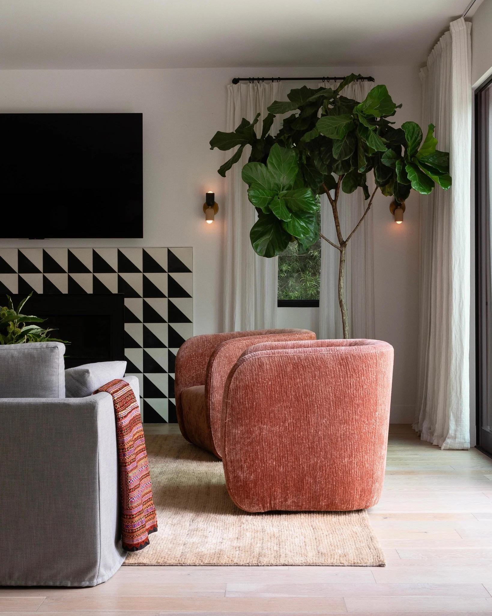 Los Angeles living room with geometric fireplace tile, sculptural lounge chairs, custom drapery and warm modern design.