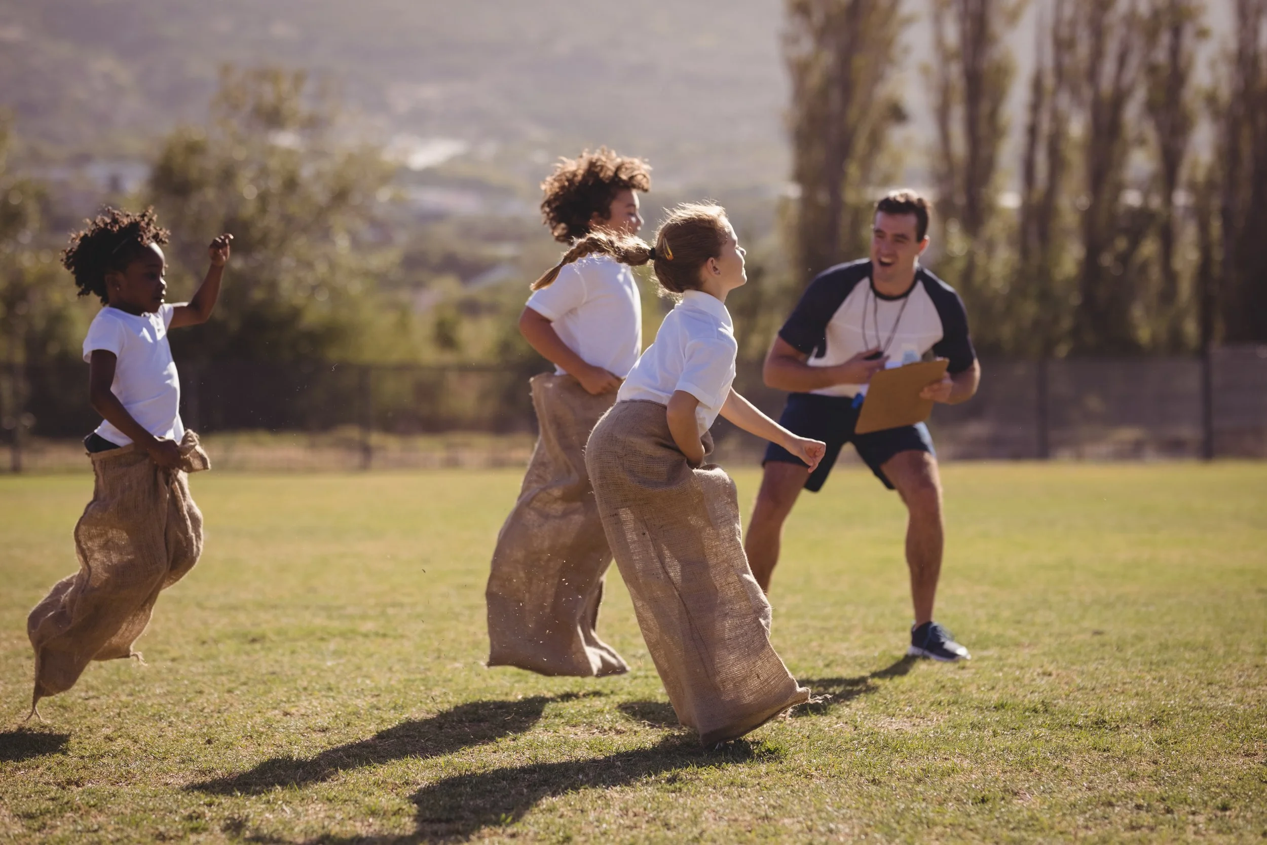 coach-cheering-schoolgirls-during-sack-race-in-par-2021-08-28-17-19-57-utc.jpg