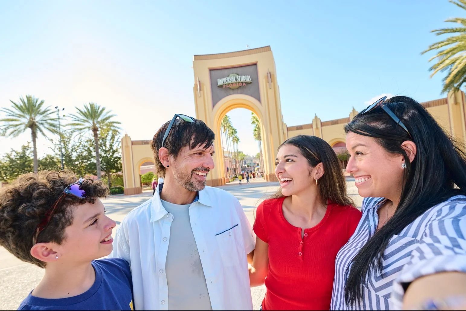 Group of five smiling people standing outside in front of Universal Studios Florida entrance gate