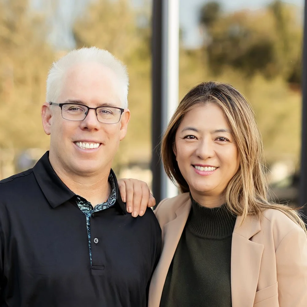 headshot of Matt MacFarland and Amanda Han standing together outside building