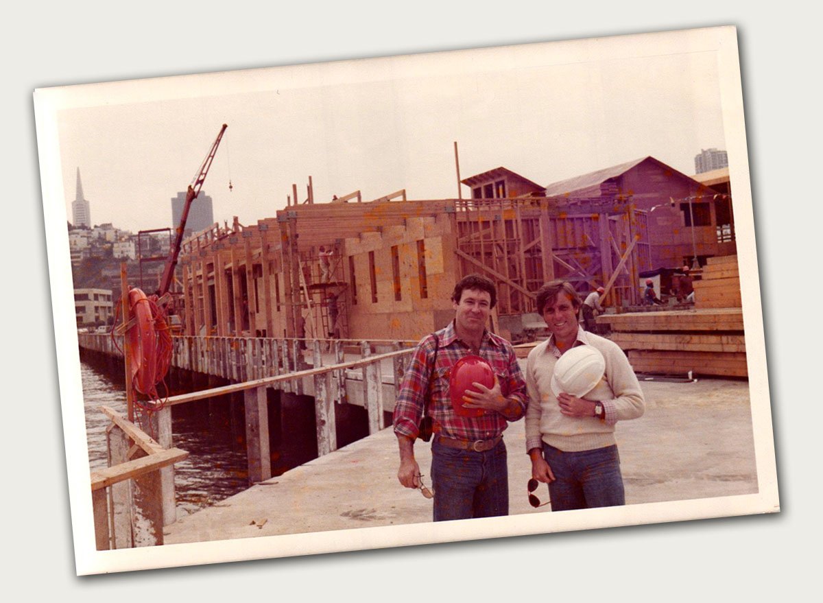 vintage photo of two men posing in front of commercial building construction site