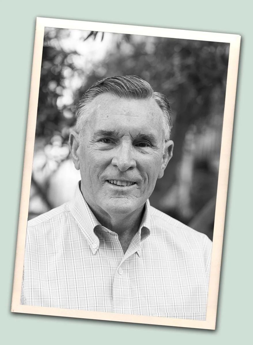 black and white photo of Patrick Furlong, an older man dressed professionally smiling at camera
