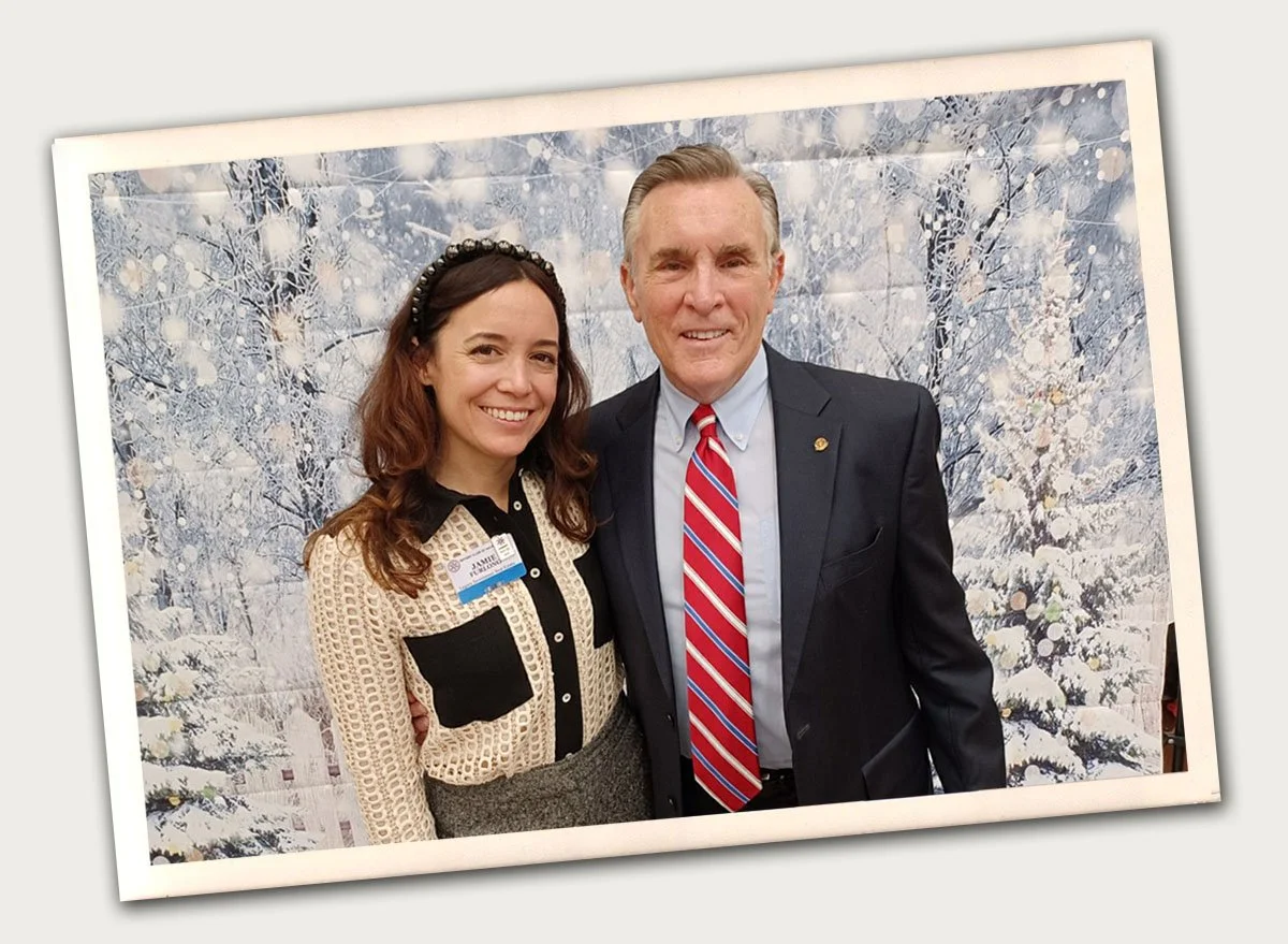 older man and his adult daughter posing and smiling in front of winter backdrop at a rotary club event