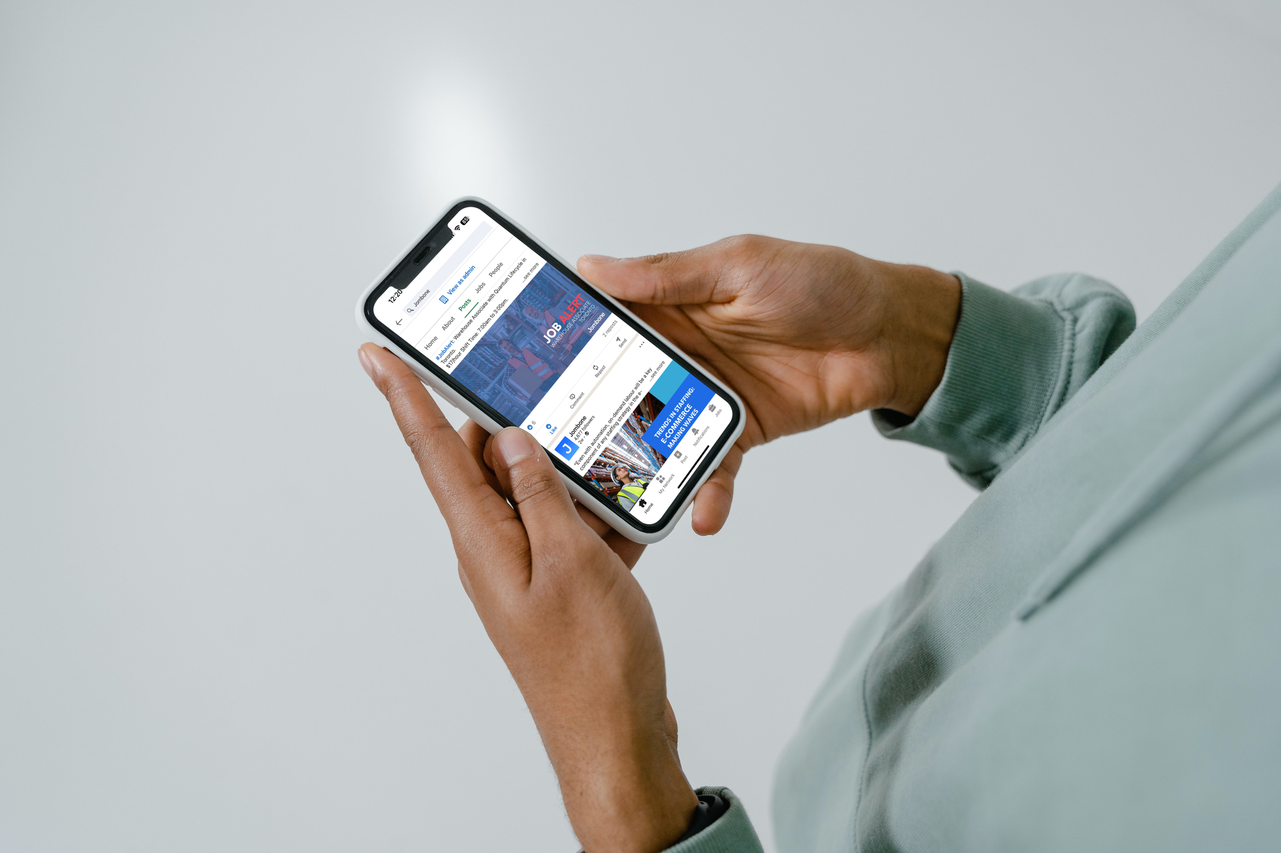 A person holding a smartphone displaying a news website with a headline about job alerts.