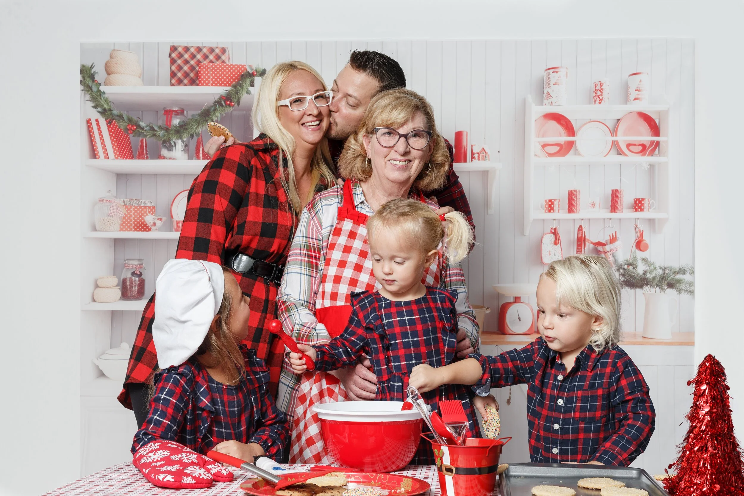 Generational Christmas photo with family in holiday kitchen baking cookies wearing matching pajamas