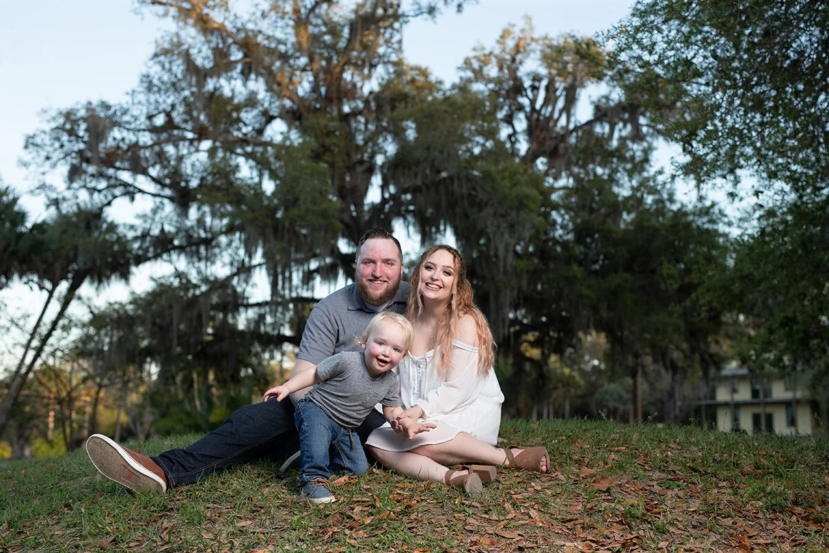 Outdoor family photo with mother, father and toddler sitting at park in Billings Montana