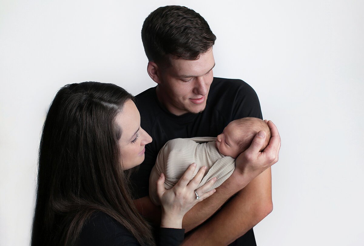 Mom and dad holding a baby for family photos near Billings, MT