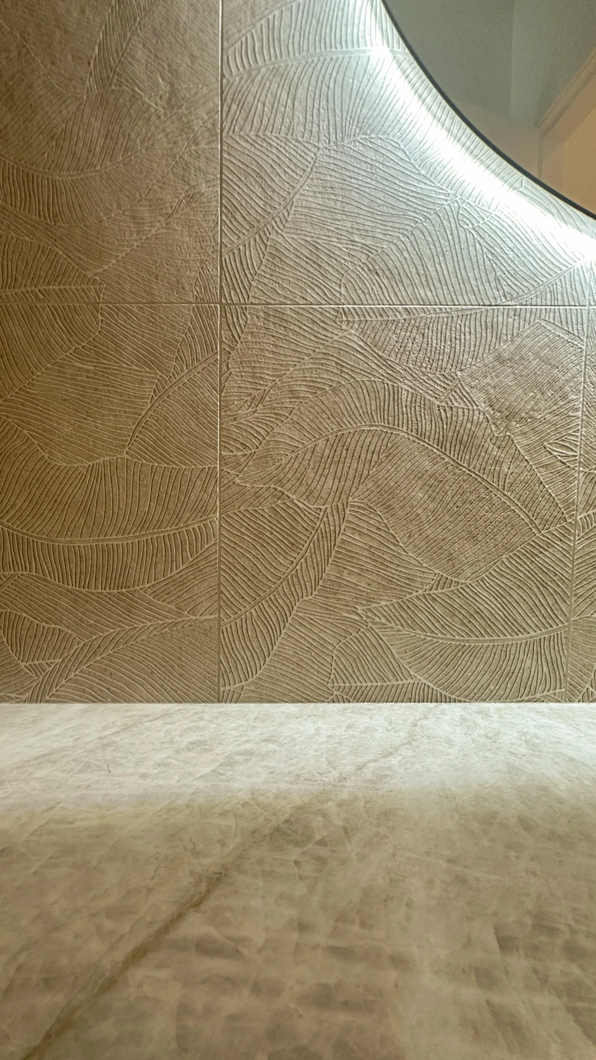 Decorative wall with a leaf pattern above a marble or stone surface.