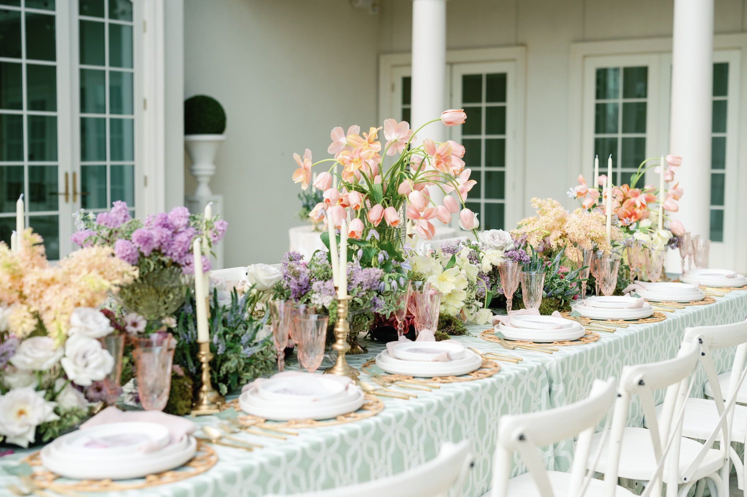 A long reception table with flowers, styled and arranged by Fashionable Florist.