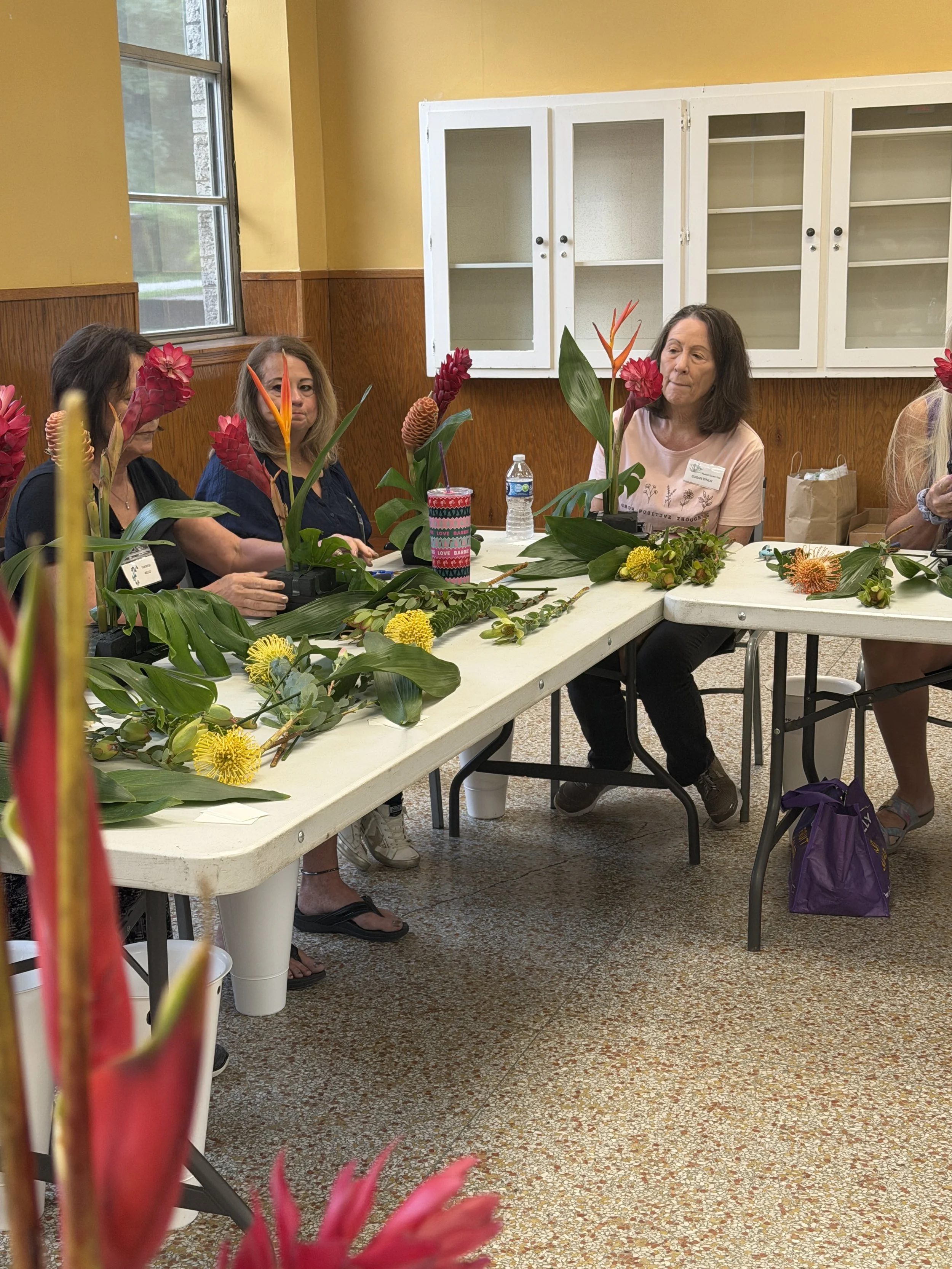 Ladies sitting at a table creating tropical flower arrangements.