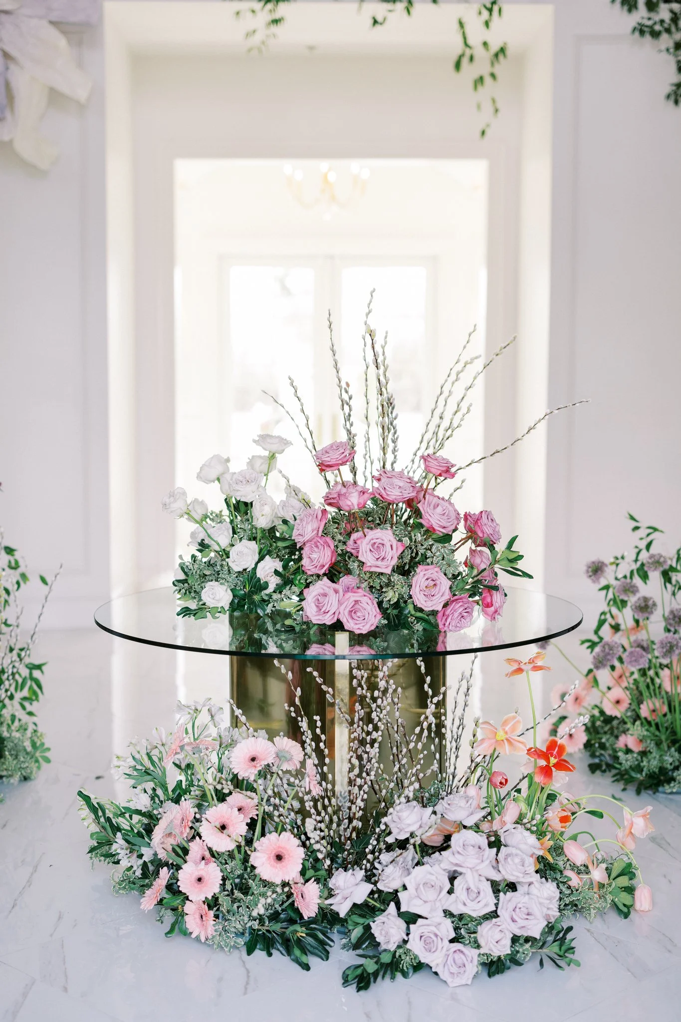 Entry table with lavender hue flowers on the table top and under the glass table.