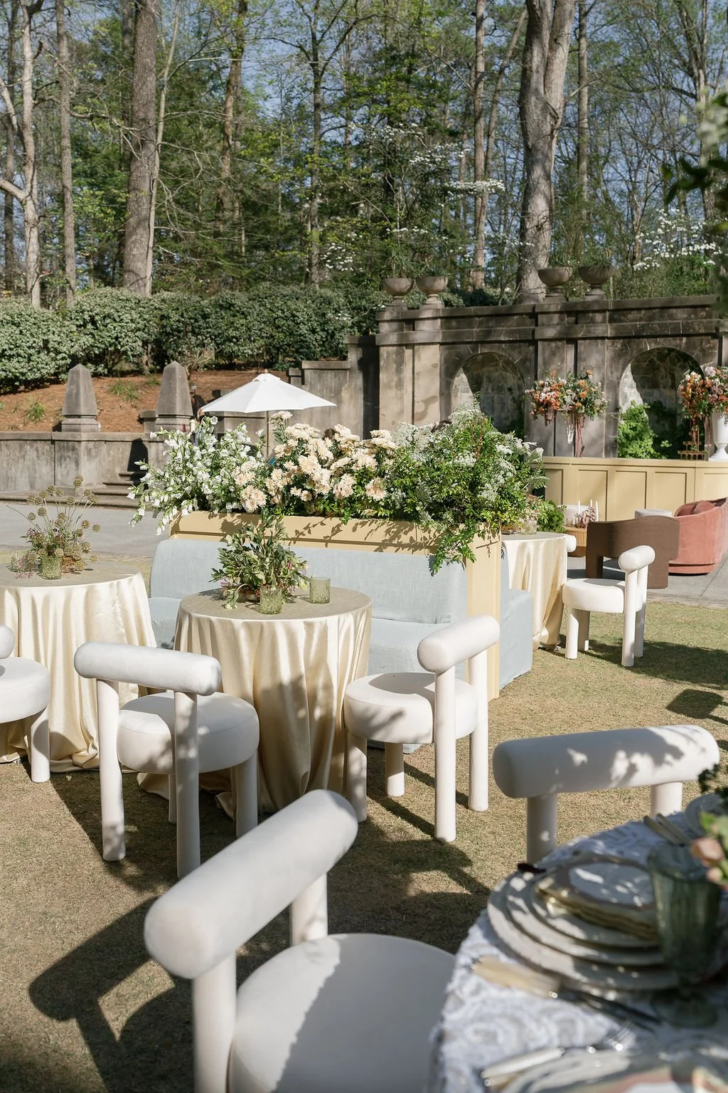 Outside small cocktail tables with seating with small flower arrangement on table.