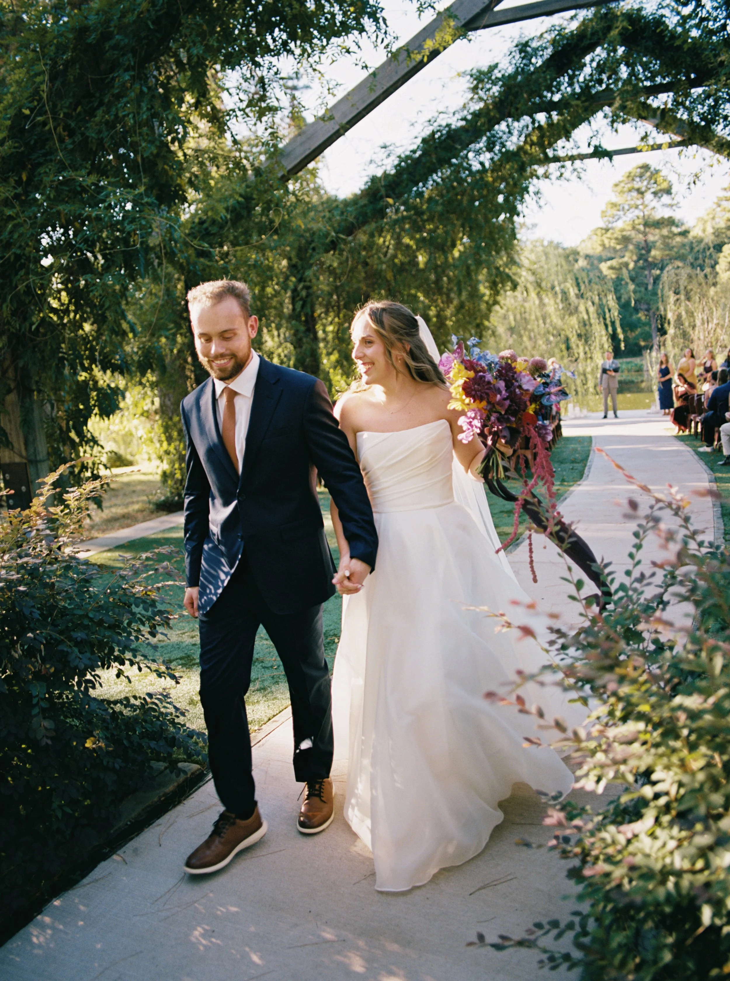 Bride and groom walking down an outdoor aisle after just getting married.