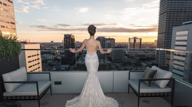 A bride is standing outside on a rooftop terrace overlooking Houston.