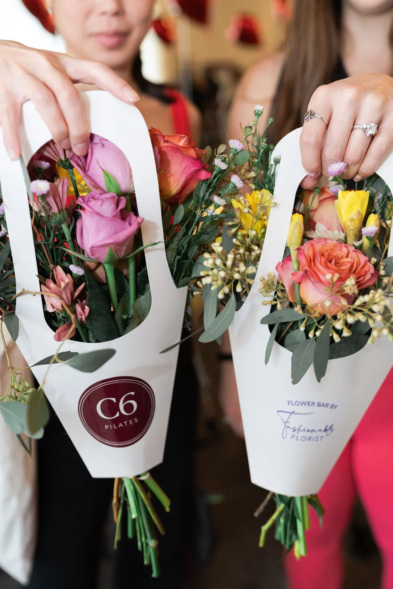 Two ladies are holding up bouquets of flowers, one says C6 Pilates and Fashionable Florist