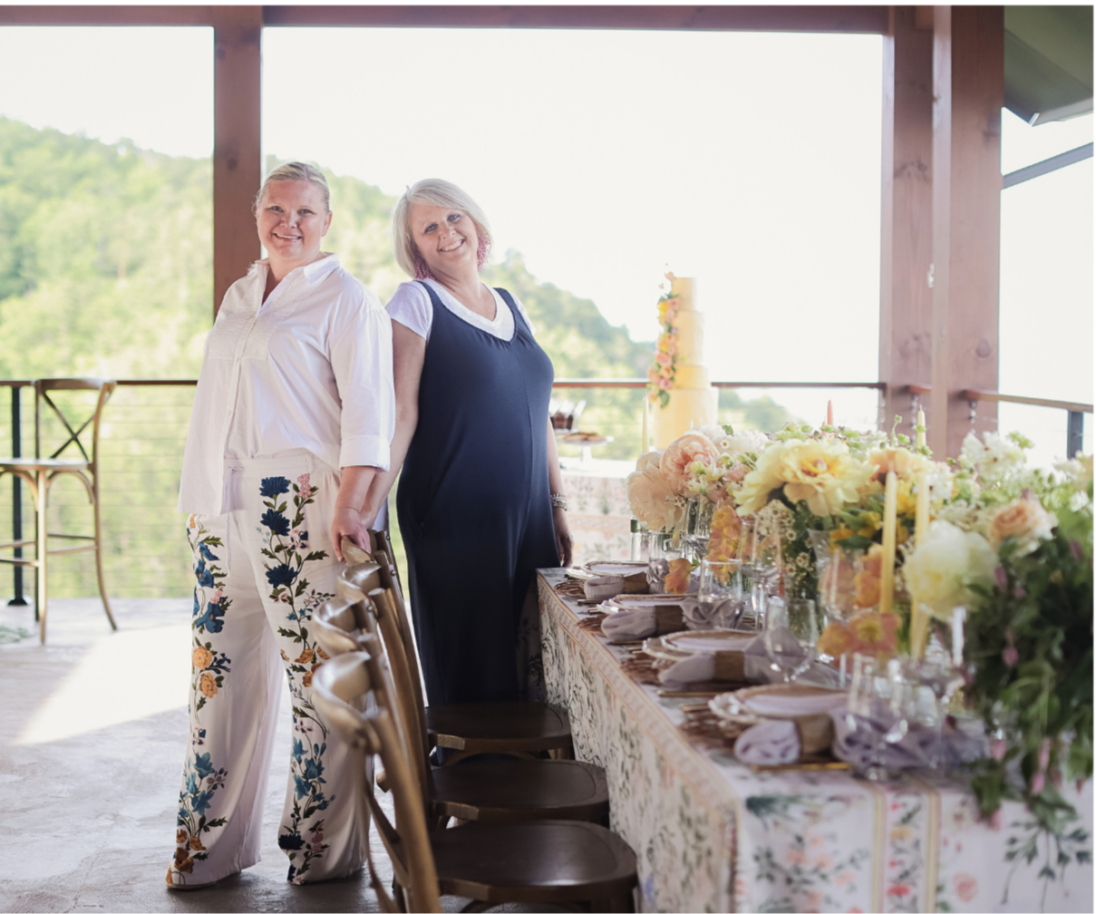 Two ladies standing next to a long table