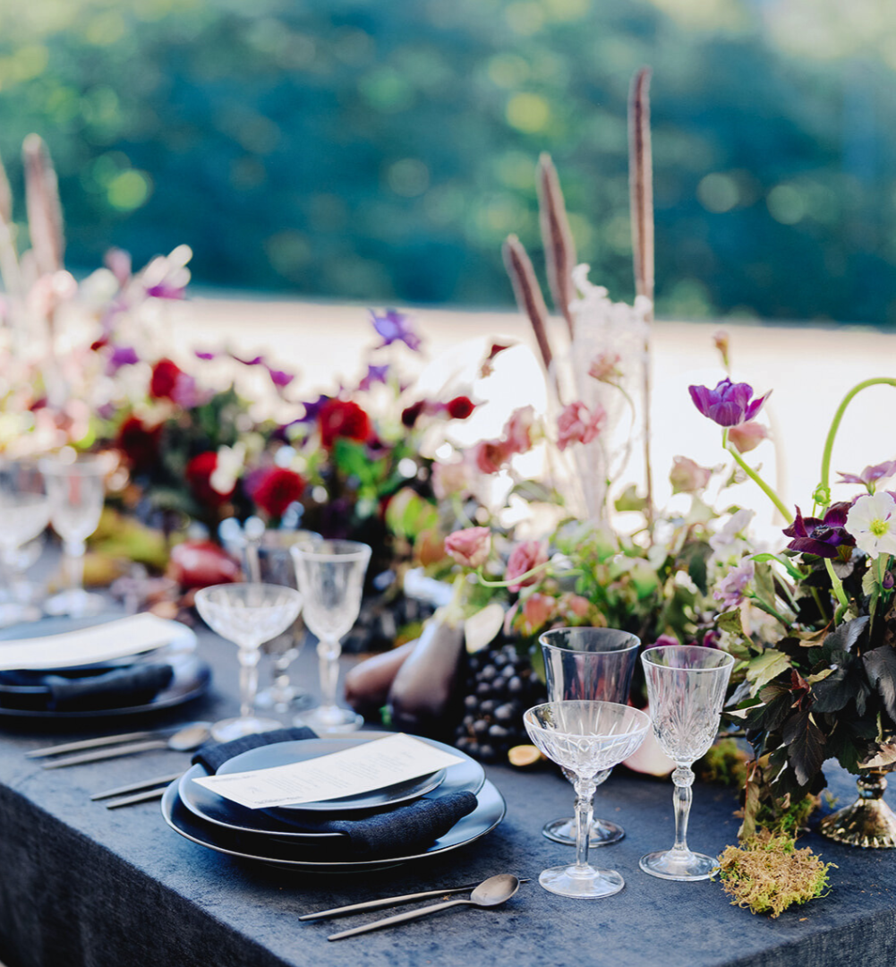 Dark tablescape adorned with flowers and produce, designed by Houston florist, Fashionable Florist.