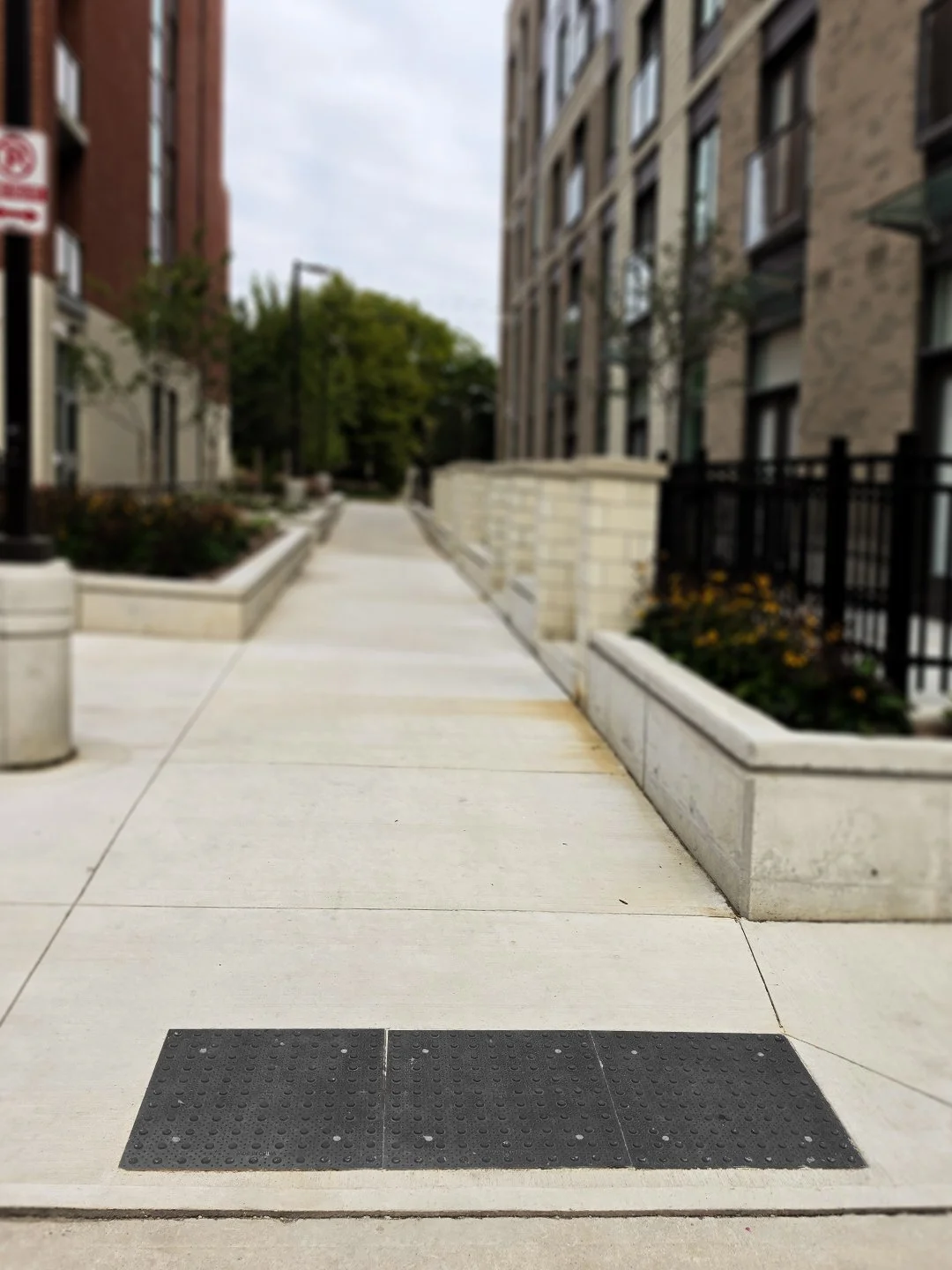 The end of a pedestrian crosswalk with GORA 24x24" onyx black steel tactile plates leading up to some apartments in London Ontario. 