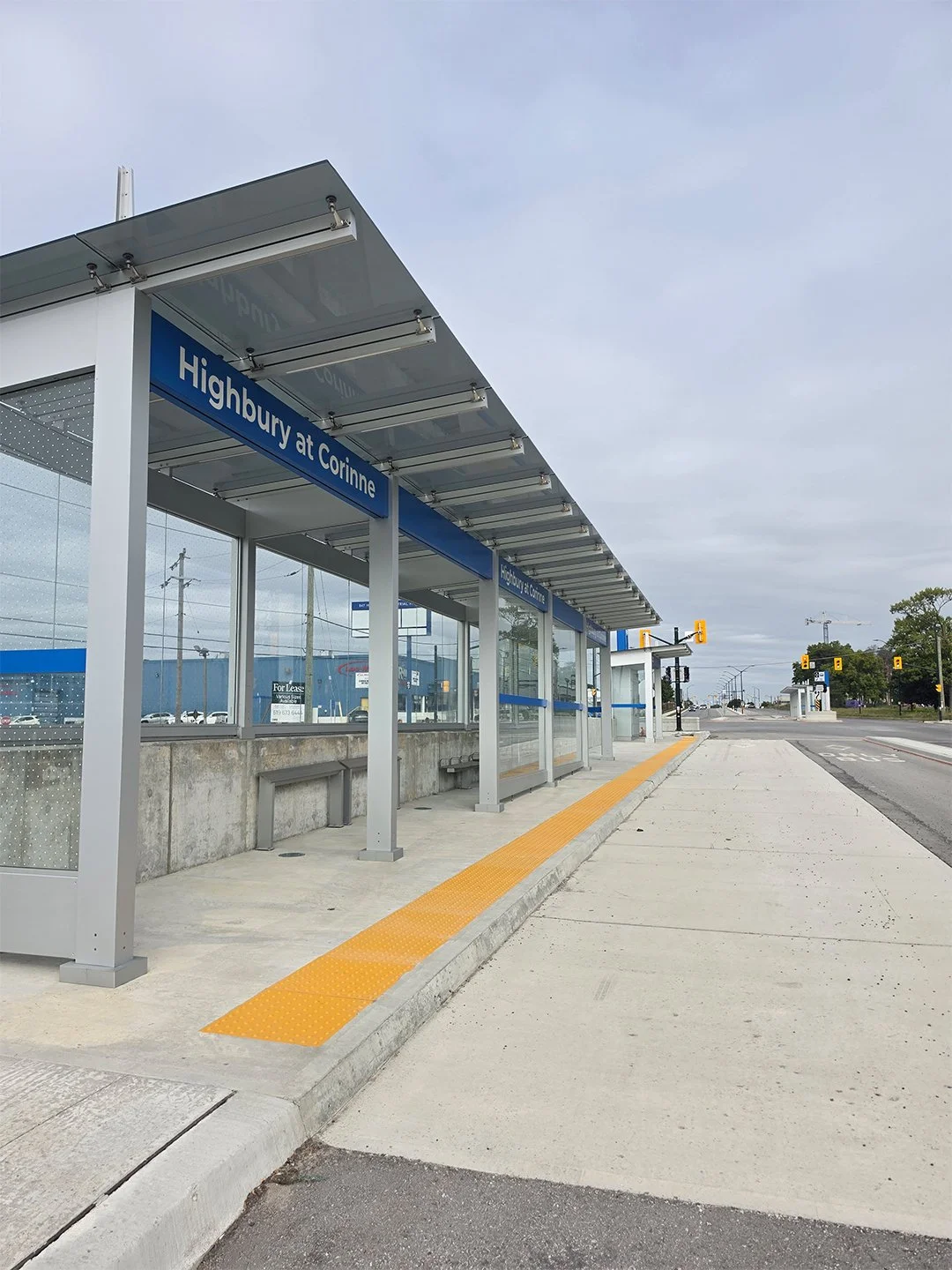 Highbury and Oxford new bus shelter in London Ontario, with GORA 24x24" safety yellow fiberglass tactile plates embedded into the concrete between the bus platform and the road.