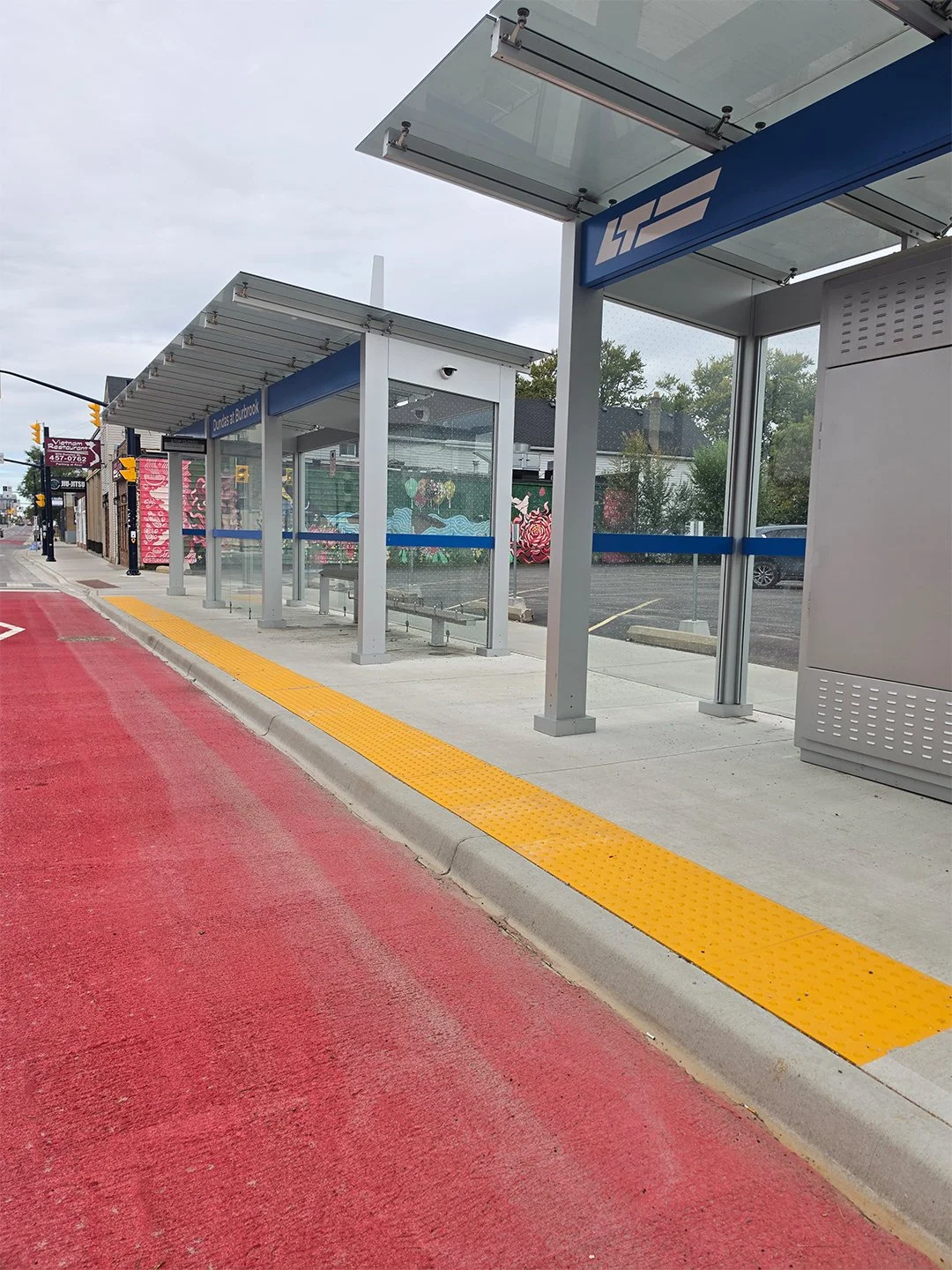 Dundas and Burbrook new bus shelter in London Ontario, with GORA 24x24" safety yellow fiberglass tactile plates embedded into the concrete between the bus platform and the road.
