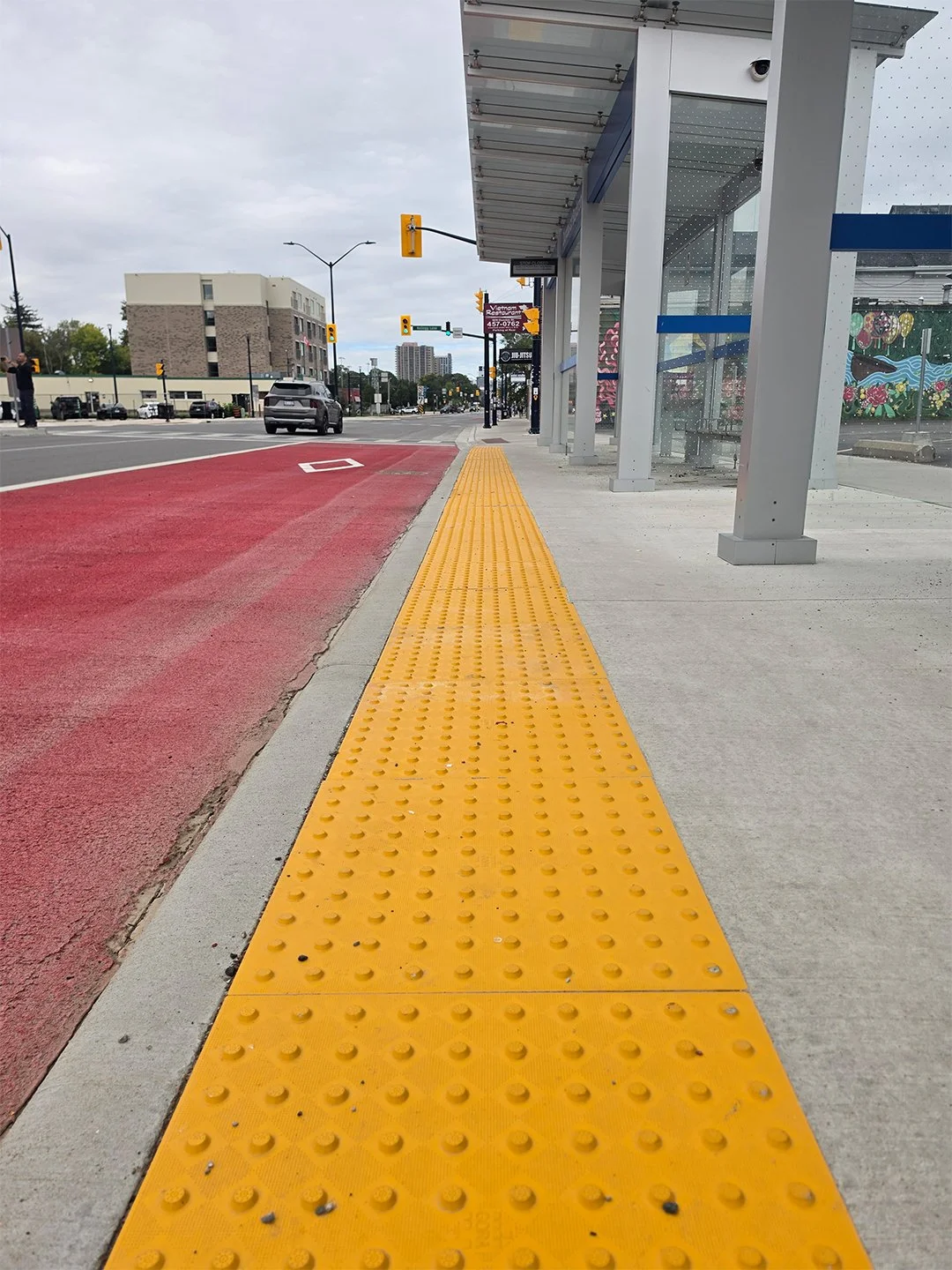 Dundas and Burbrook new bus shelter in London Ontario, with GORA 24x24" safety yellow fiberglass tactile plates embedded into the concrete between the bus platform and the road.