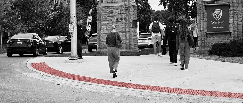 A group of students walking over GORA brick red steel tactile and radial plates heading towards Western University in London Ontario.