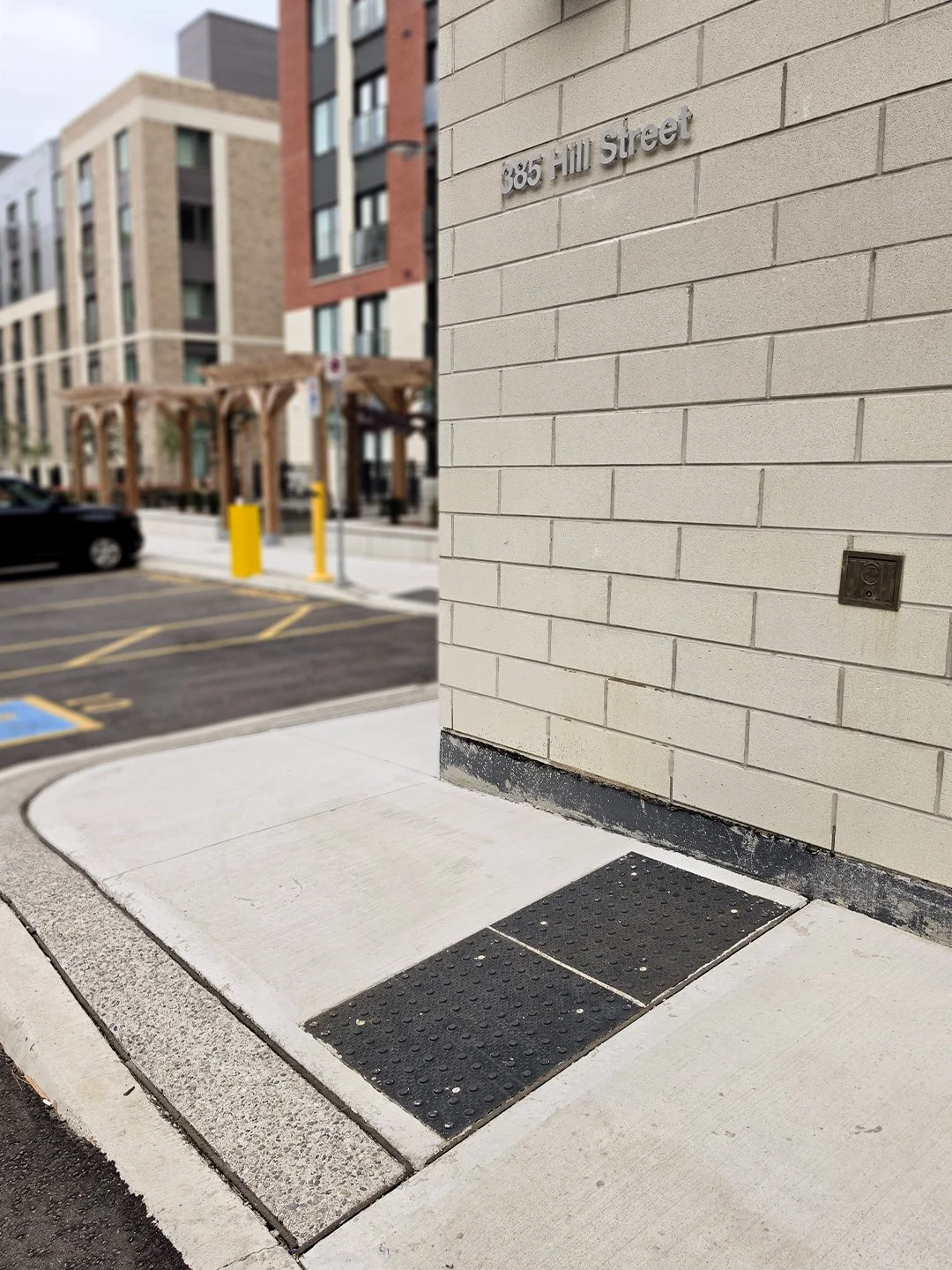 Sidewalk at 385 Hill Street Apartment complexes in London Ontario, GORA 24x24" onyx black steel tactile plates indicate a pedestrian crossing.