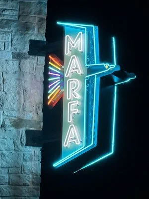 Custom made, old school, real, Neon sign spelling 'MARFA' with colorful radiating lines. Youthful environment.