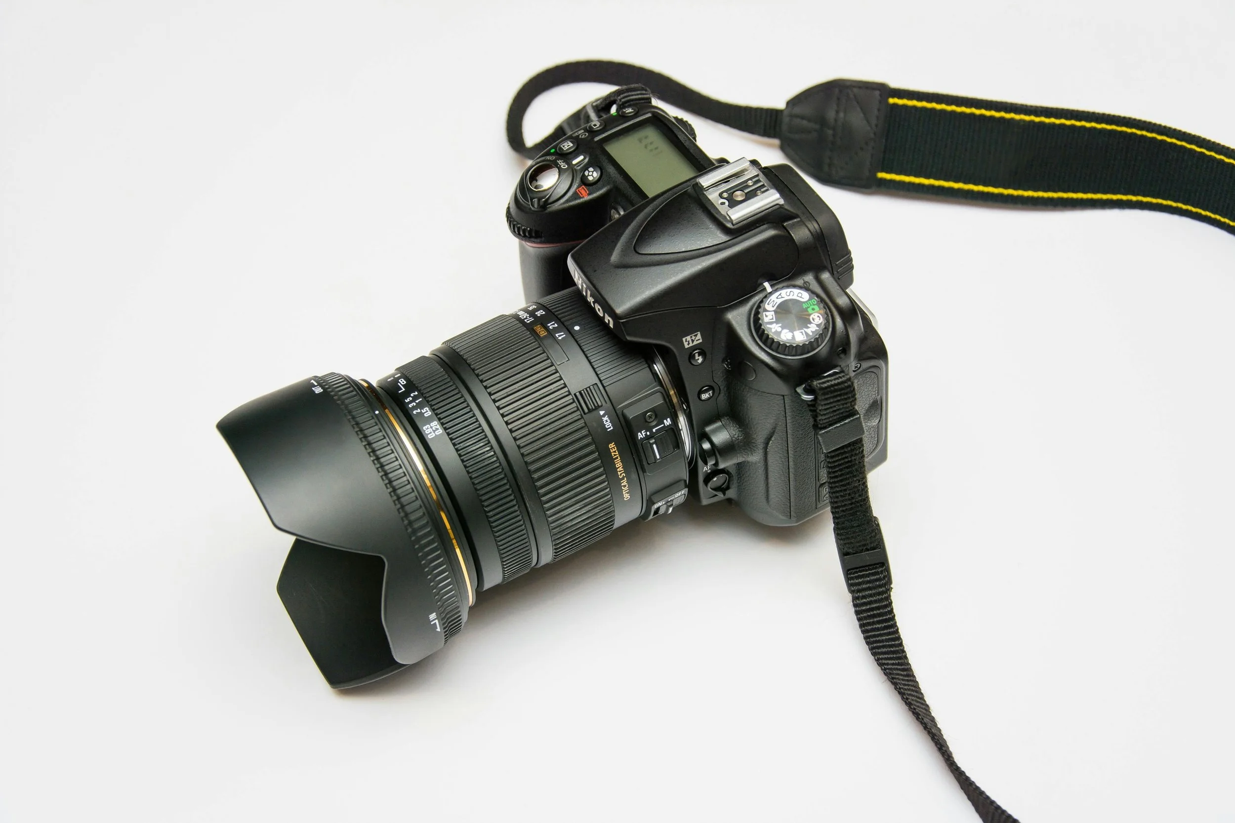A digital camera with a long lens and a camera strapped attached.