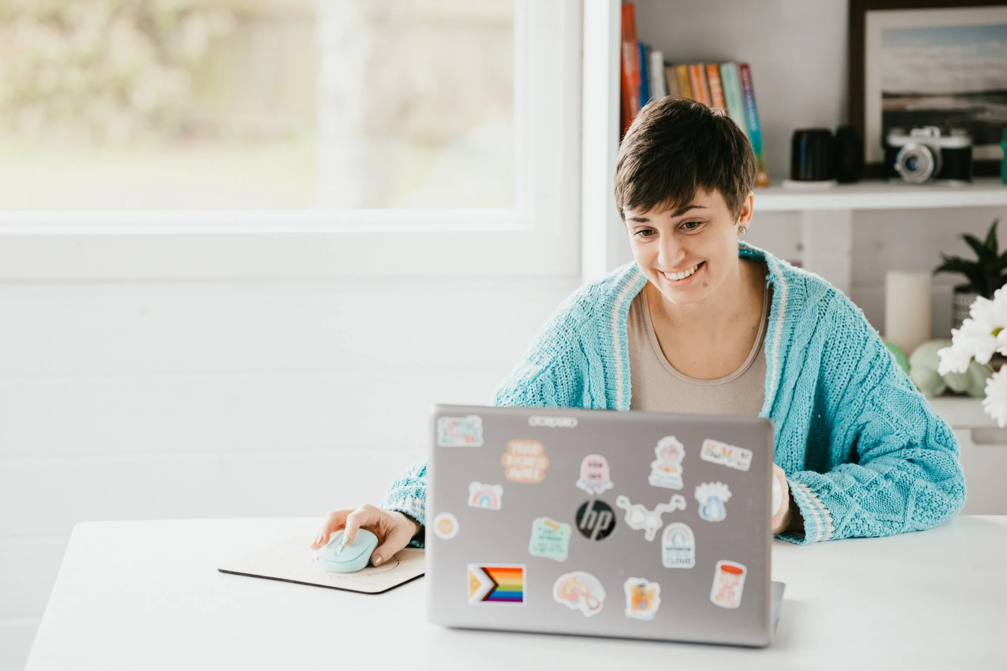 Jen, hypnotherapist, sitting at a desk, wearing a blue cardigan, smiling at her laptop screen