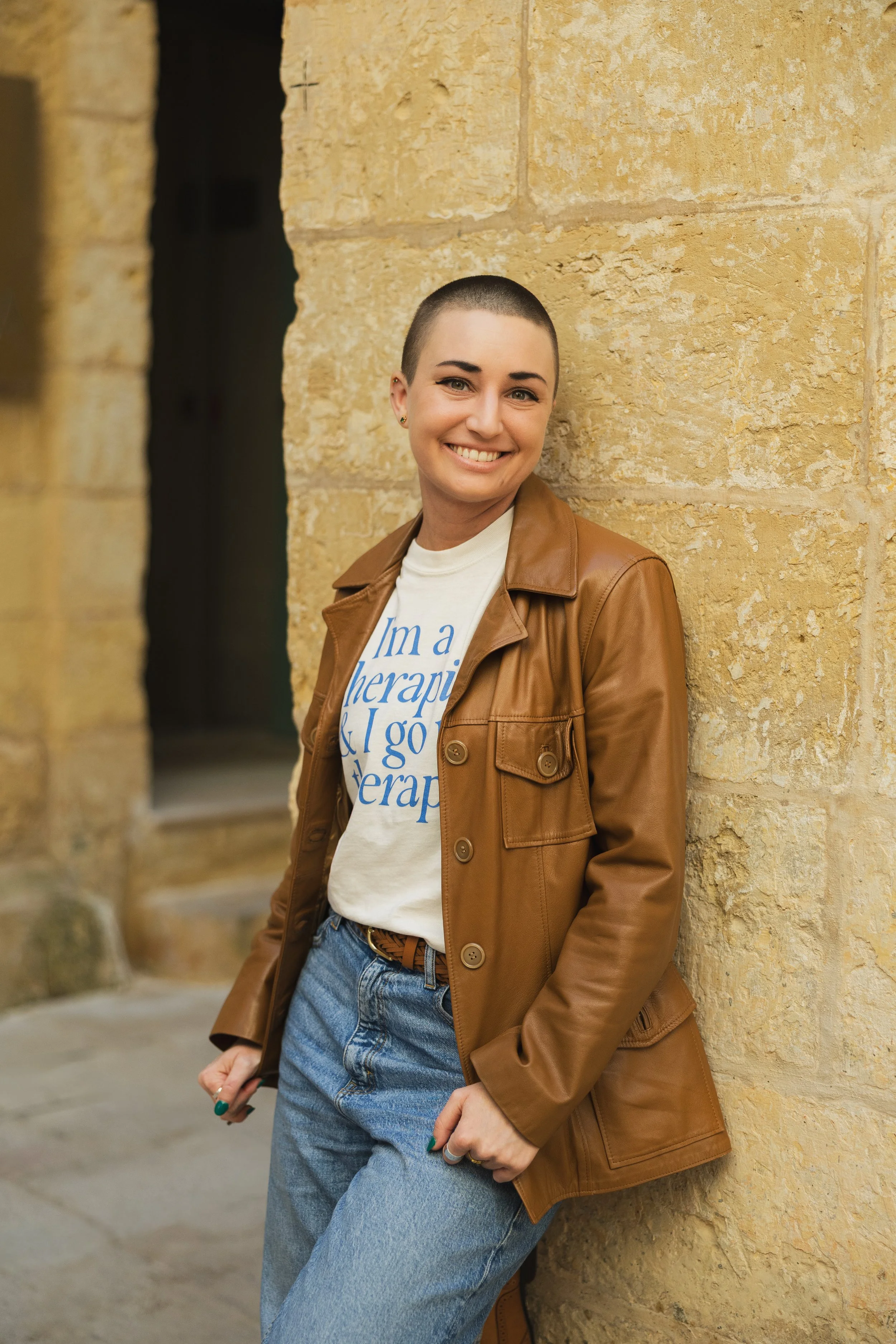 Hypnotherapist Jennifer Austin smiling in front of a stone wall