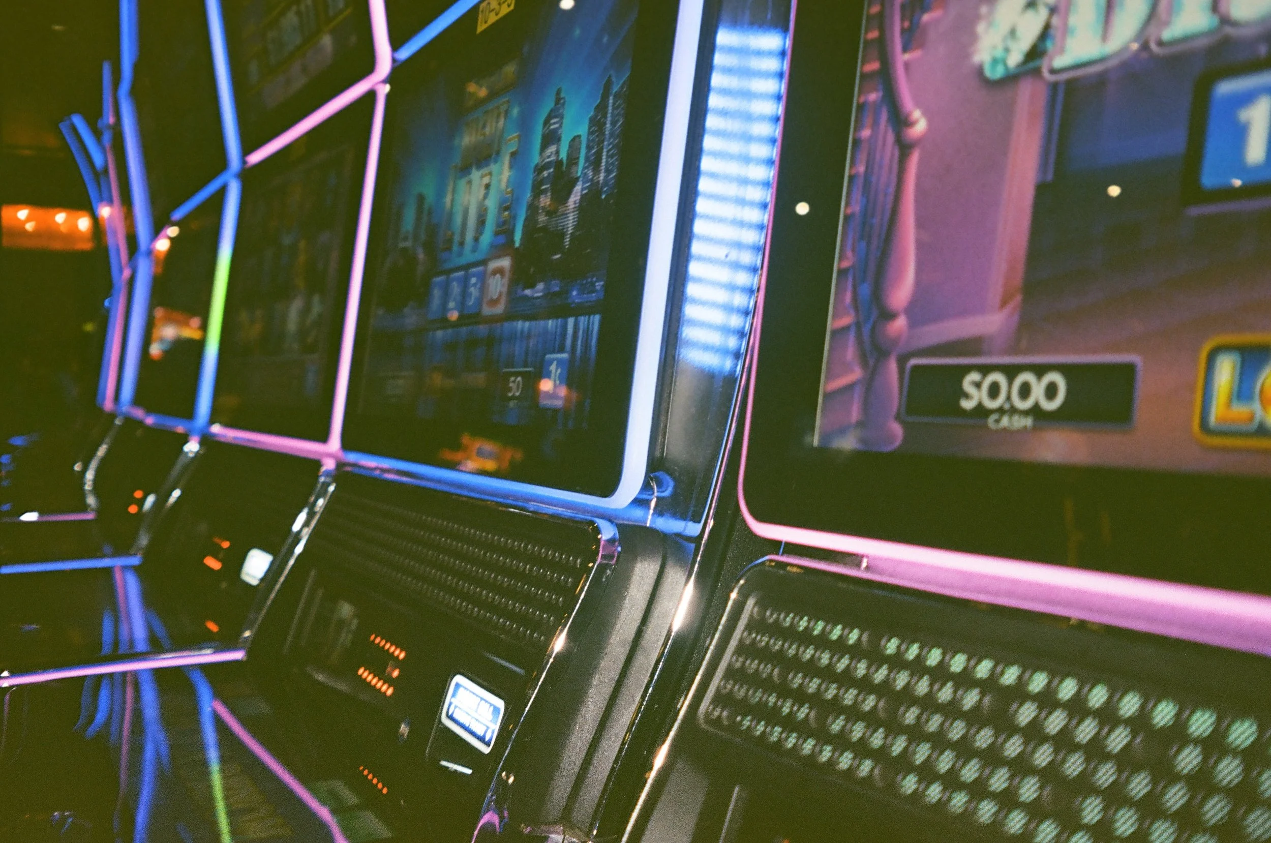 Close-up of two slot machines with colorful neon lights and digital screens displaying game graphics.