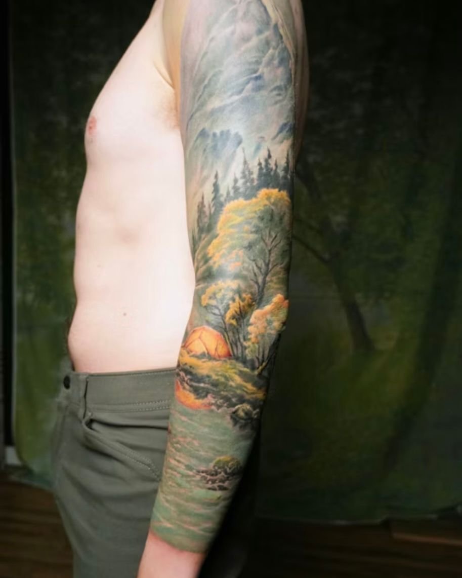 Looking back on this epic landscape sleeve for Nich. 🌲🏔️

What started as a black and gray half sleeve idea turned into a full color scene with snow-capped mountains, evergreen trees, a glowing tent, and a rocky stream reflecting the sky. Every det