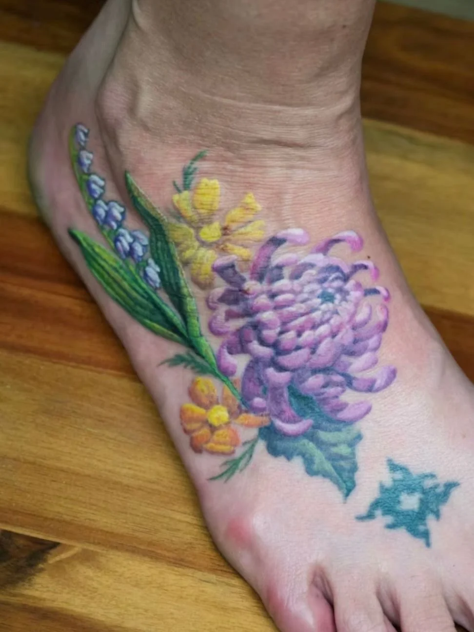 Here is the finished piece.

The lily of the valley leaves are botanically correct now, the chrysanthemum and cosmos are in, and everything flows together the way her foot deserved.

Laura has been living with something that bothered her for years. N