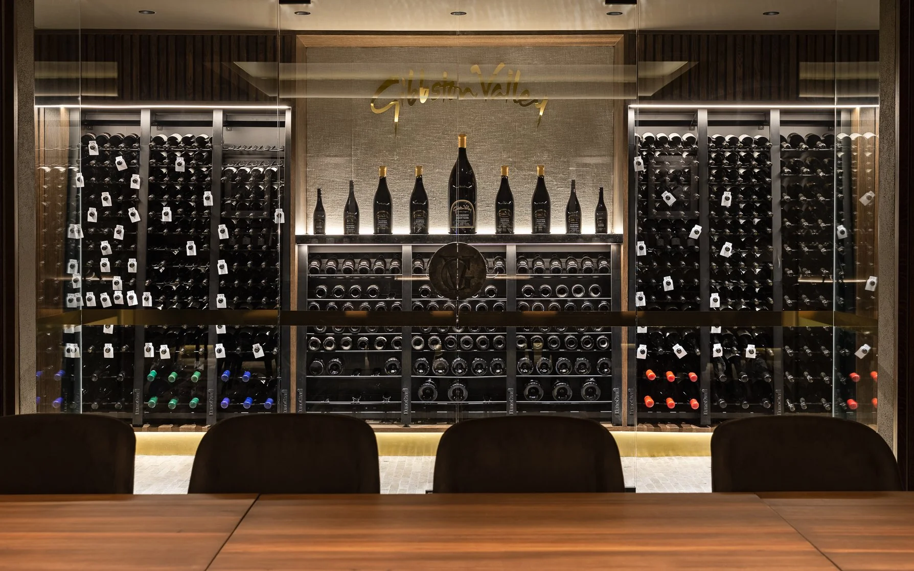 Gibbston Valley Lodge's cellar with rows of their vineyard's wine on display and a large meeting table in the centre.