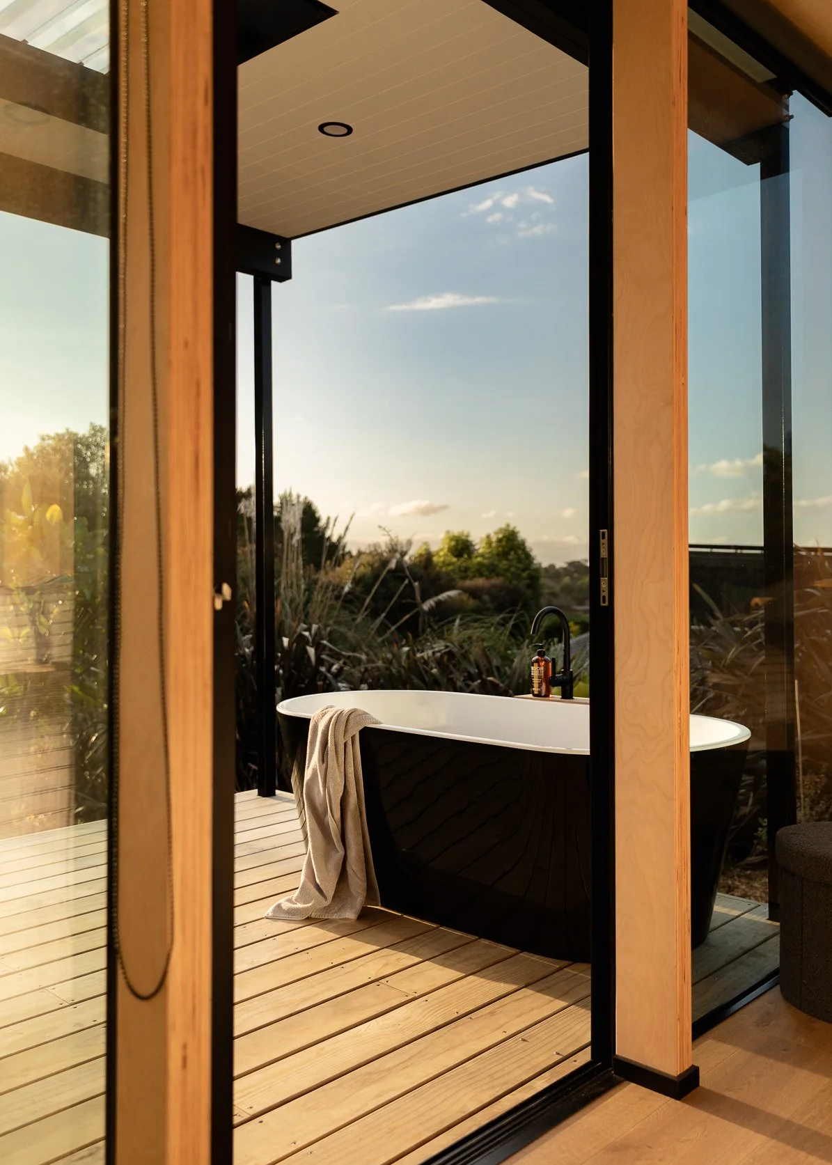 A black outdoor bath viewed from Master Bedroom with sunset in background.