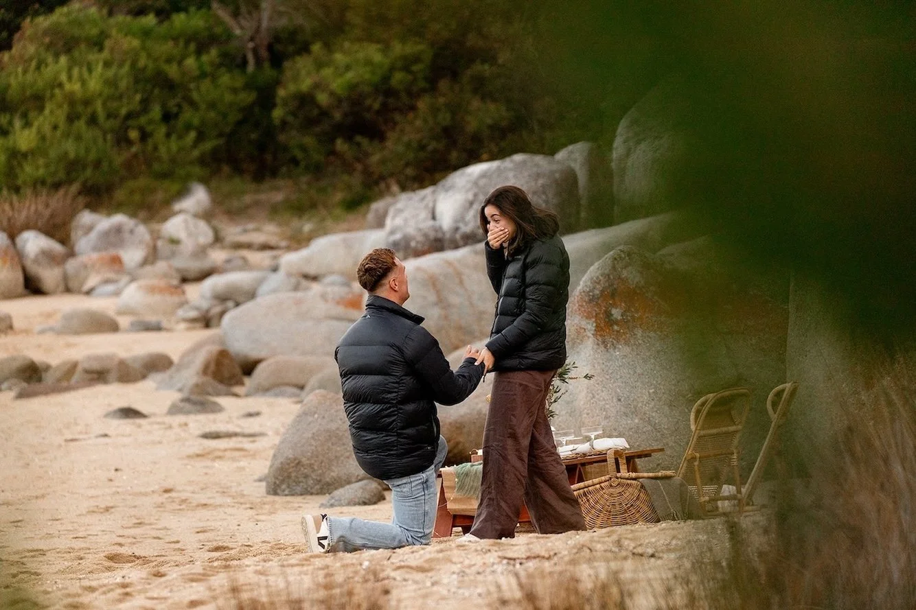 Man proposing to his surprised partner on a rocky beach in Tasmania