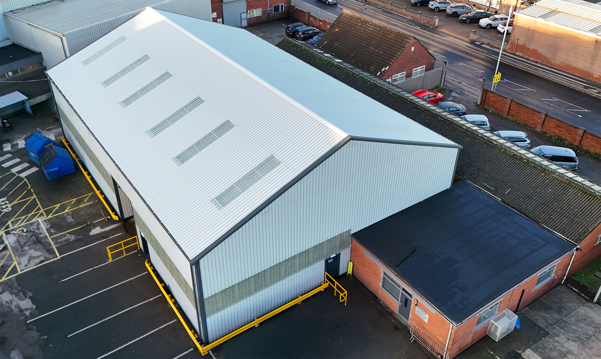 Grey Cladded Garage Building with a red bricked flat roof in front.