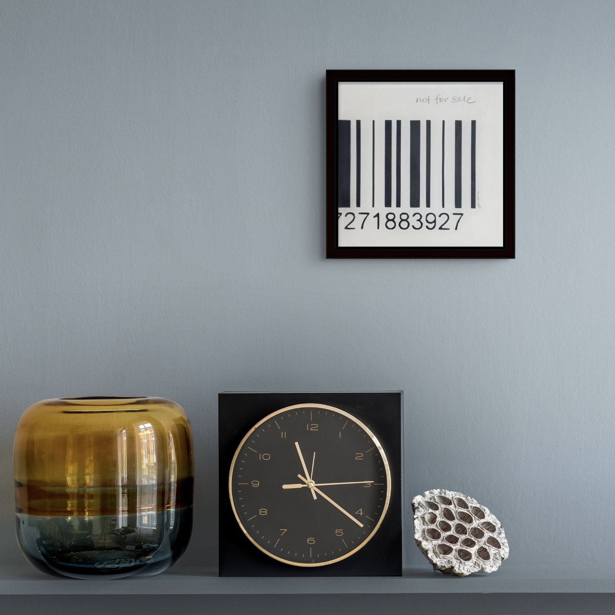 Not for Sale, a small framed black-and-white feminist barcode artwork by Alissa Van Atta, displayed on a gray wall above a console with decorative accessories.