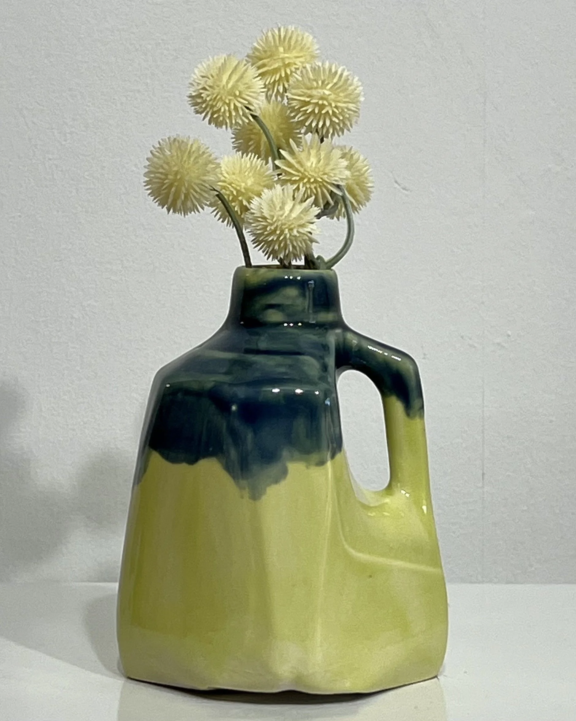Handmade porcelain milk jug vase 26.123 by Alissa Van Atta, featuring bright yellow-green Pear glaze with deep blue-green Deep Sea glaze flowing over the shoulders, styled with flowers.
