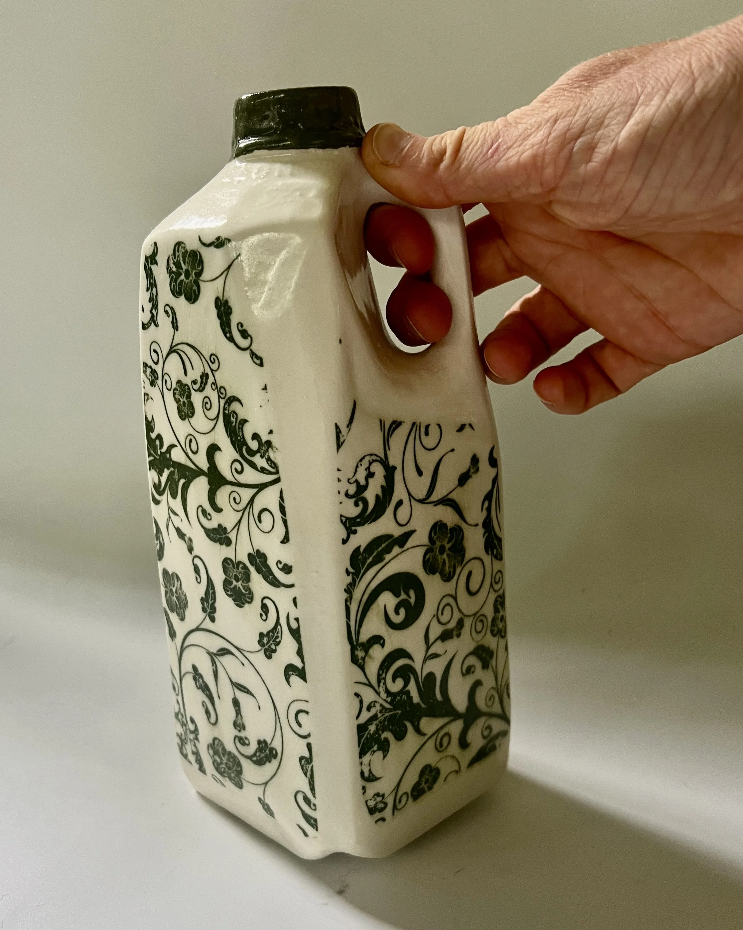 Botanical tall porcelain milk jug shown in hand to demonstrate scale and proportions.  8. Detail image